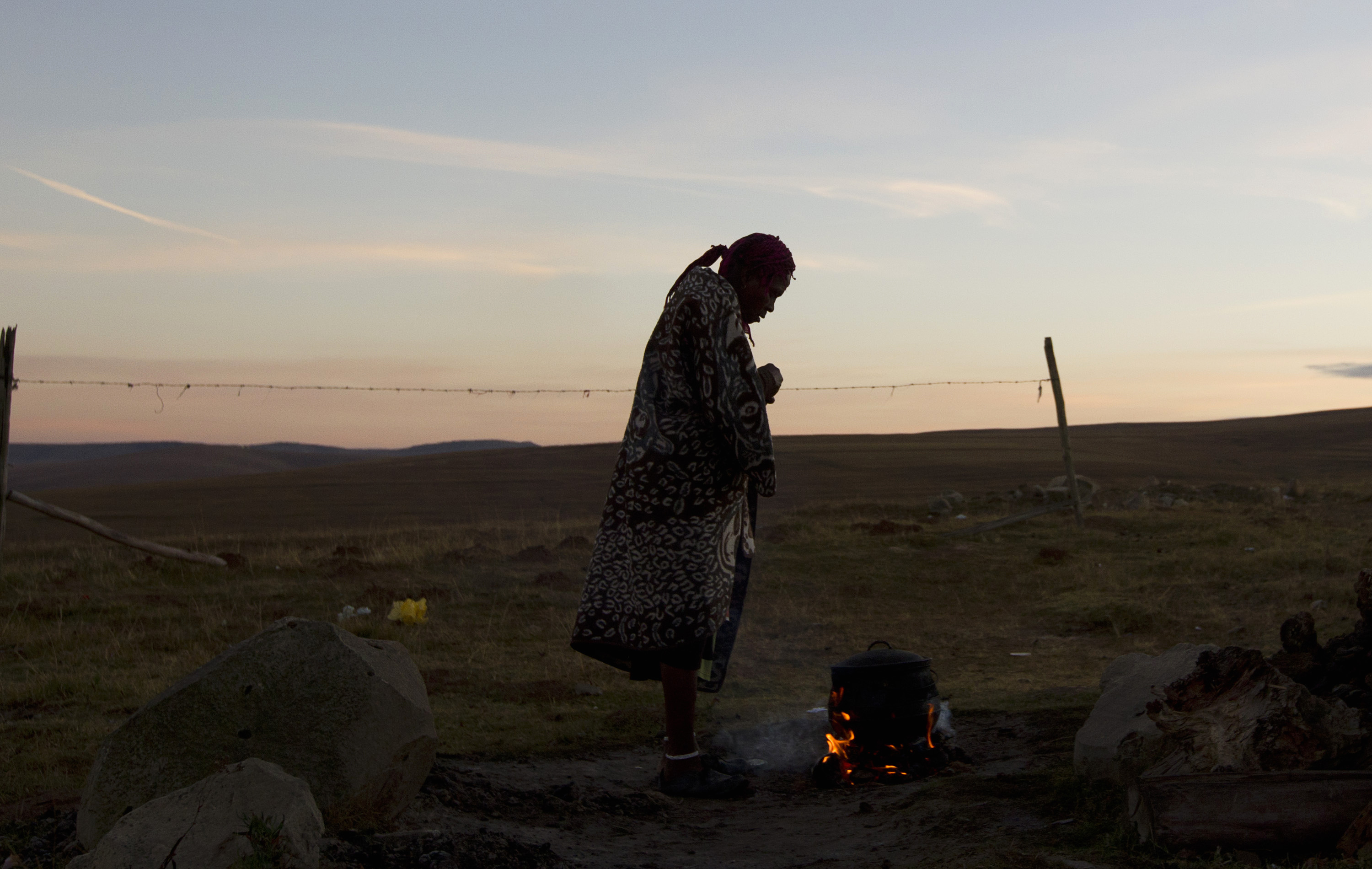 A woman warms water on an open fire near the home of former South African President Nelson Mandela's house in Qunu