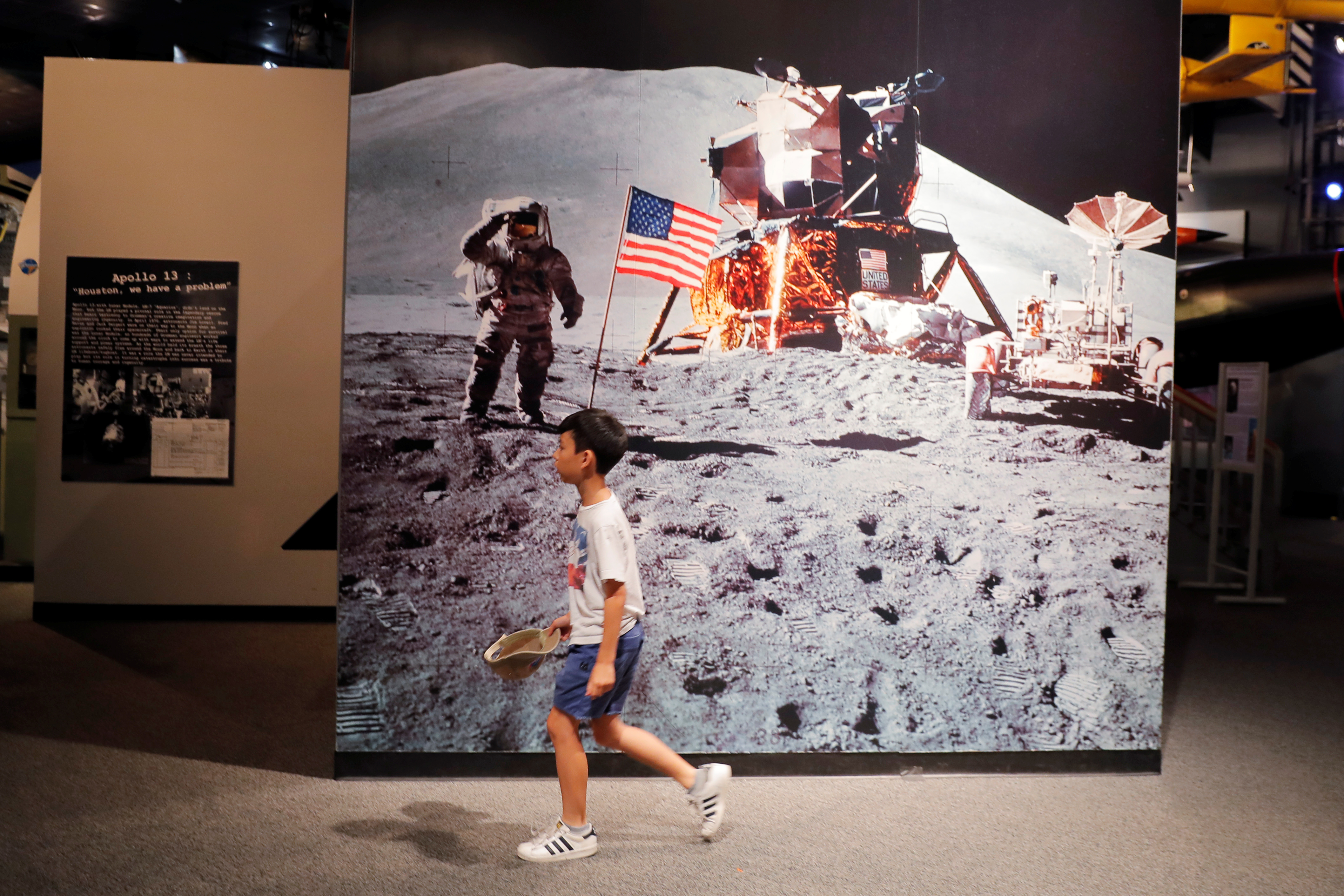 A young boy walks past a photograph of Buzz Aldrin on the surface of the moon during the Apollo 11 mission at the Cradle of Aviation Museum in Garden City, New York