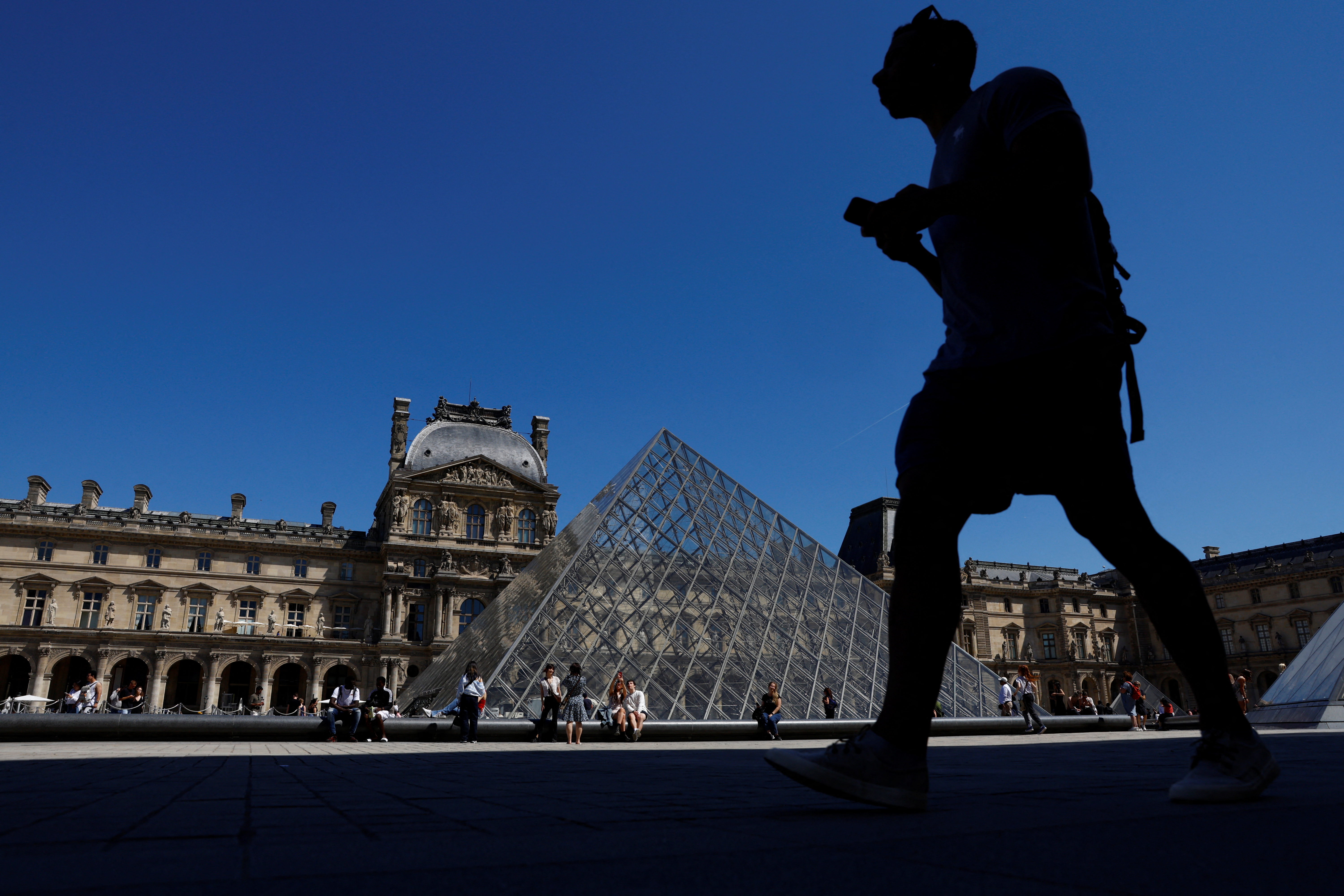 A man walks near the glass Pyramid of the Louvre museum in Paris