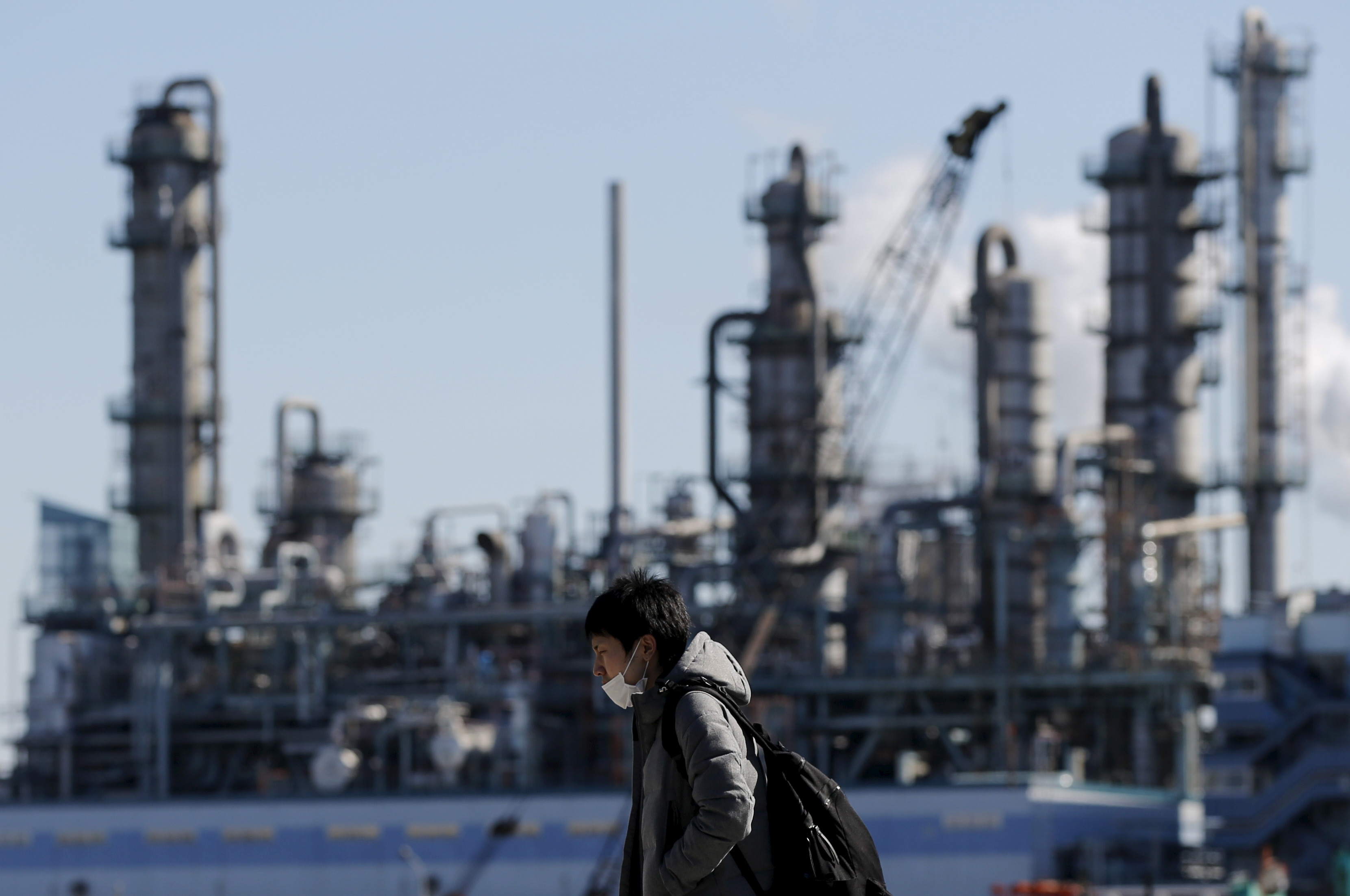 Worker walks near a factory at the Keihin industrial zone in Kawasaki