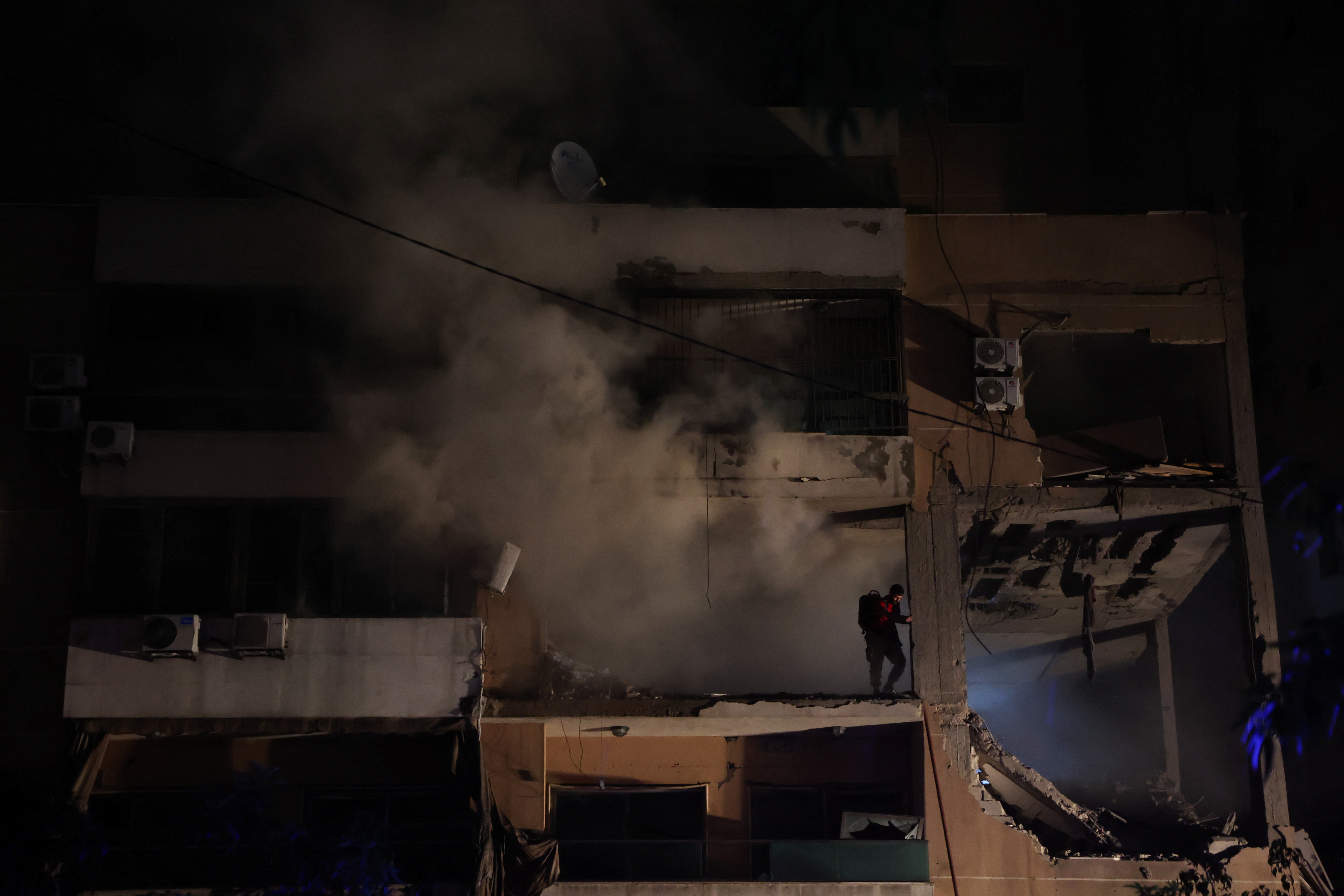 Smoke rises as a man stands on a damaged building at the site of an explosion, in what security sources say is an Israeli drone strike, in the Beirut suburb of Dahiyeh