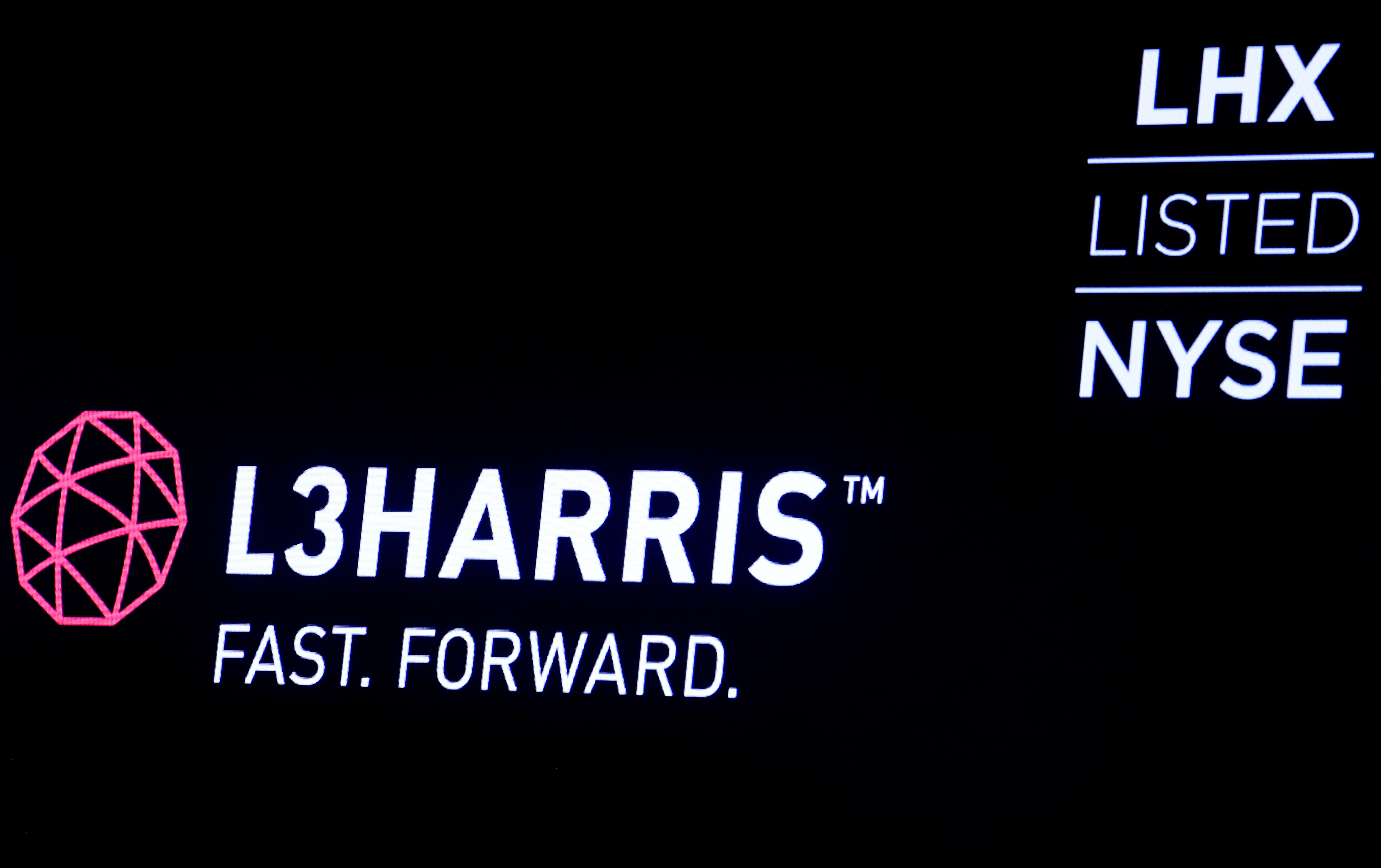 The logo and ticker for L3Harris are displayed on a screen on the floor of the NYSE in New York