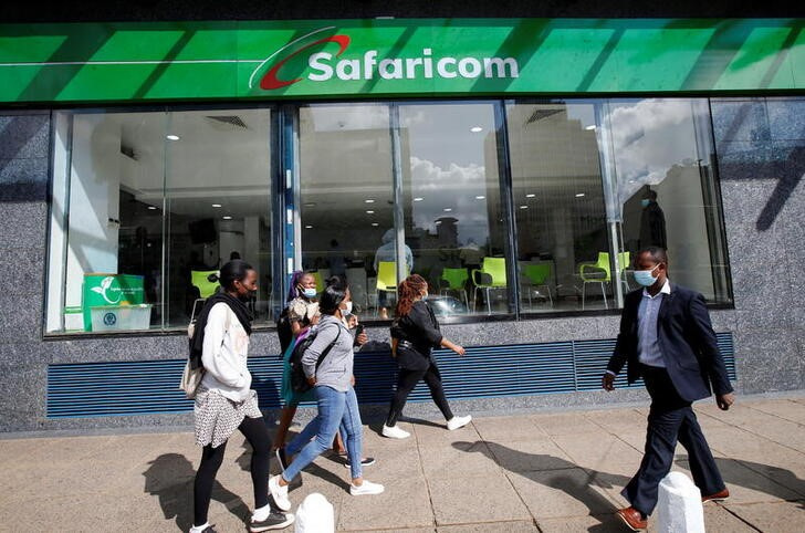 Pedestrians walk on a sideway outside the Safaricom mobile phone customer care centre in the central business district of Nairobi