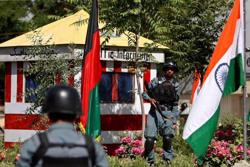 Afghan policemen stand guard next to Indian and Afghan national flags, at a check point in Kabul city
