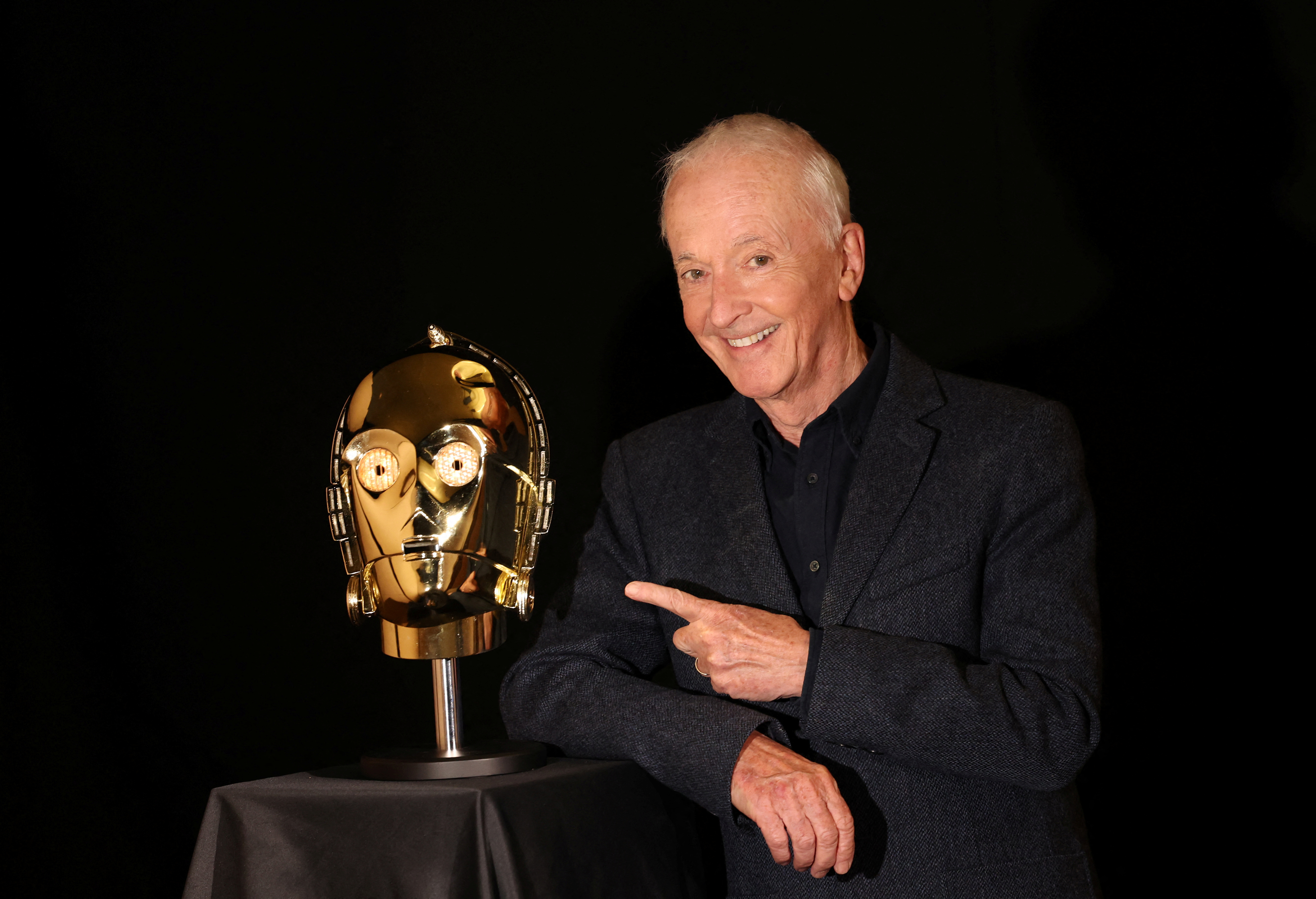 Actor Daniels, who played C-3PO in 11 Star Wars films, poses next to a screen-matched, light-up C-3PO head from the 1977 film 'Star Wars: A New Hope'