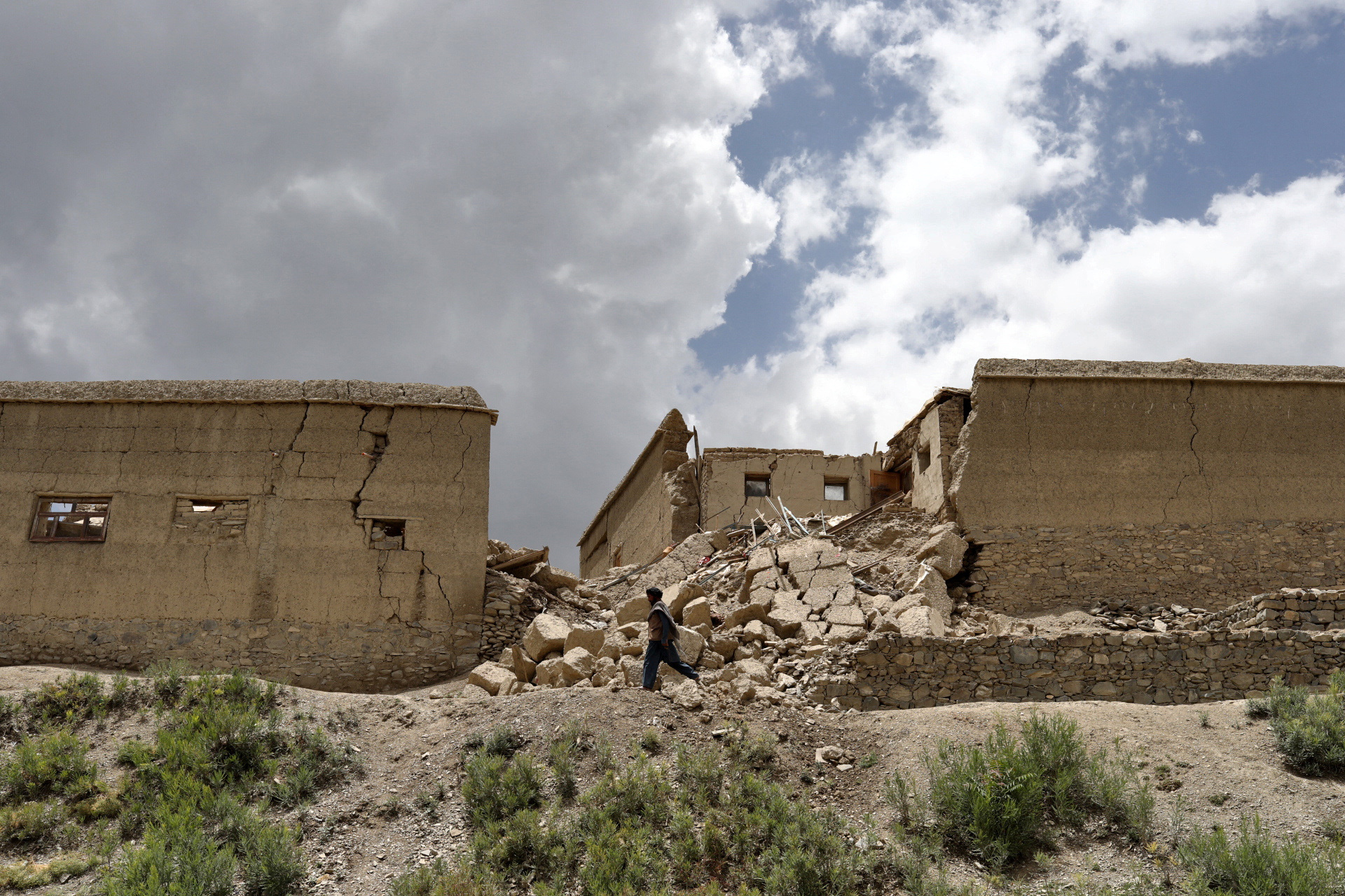 An Afghan man walks past a house that was damaged by an earthquake in Gayan