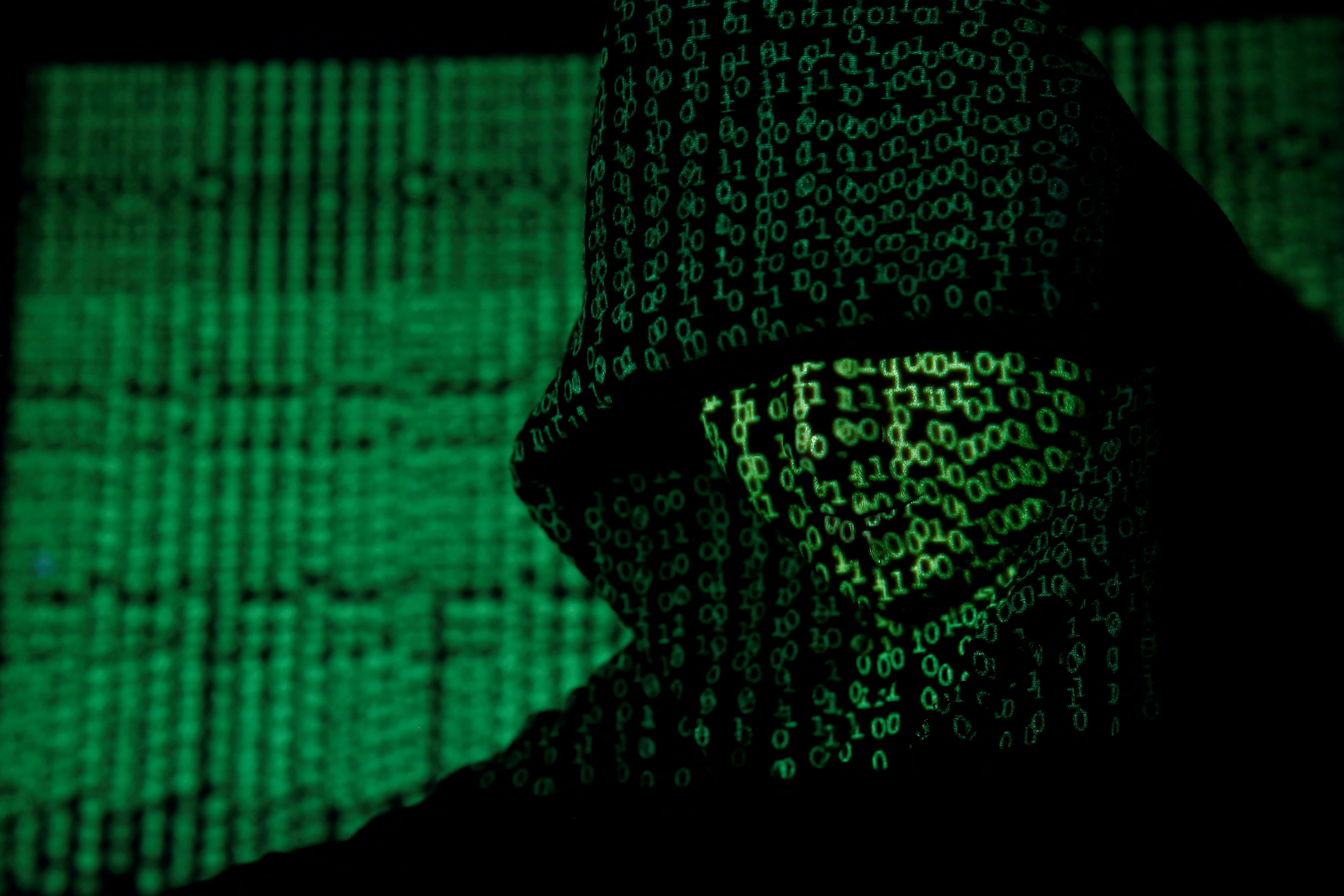 Projection of cyber code on hooded man is pictured in this illustration picture