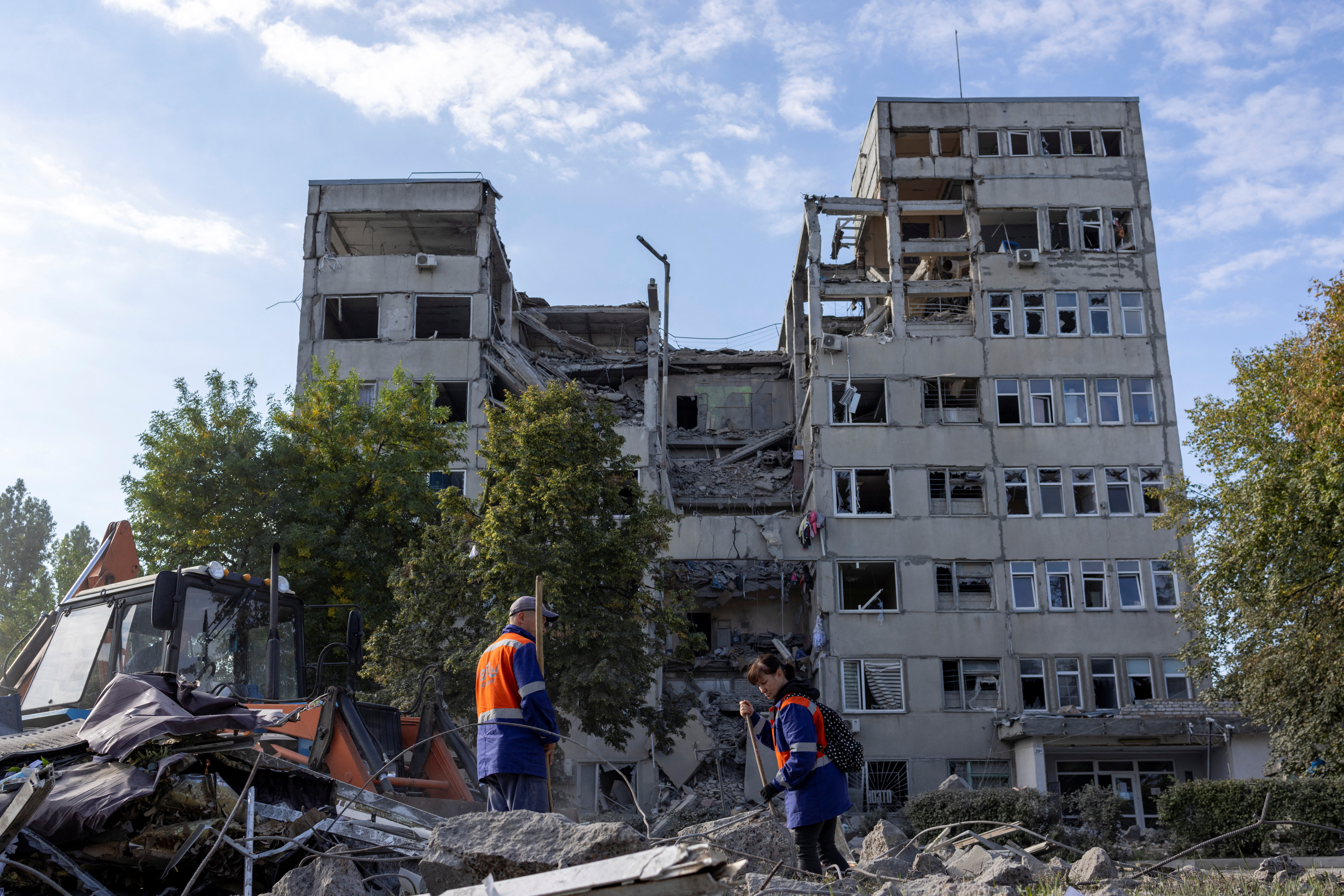 Workers clean the debris of an office building destroyed by a strike in Mykolaiv