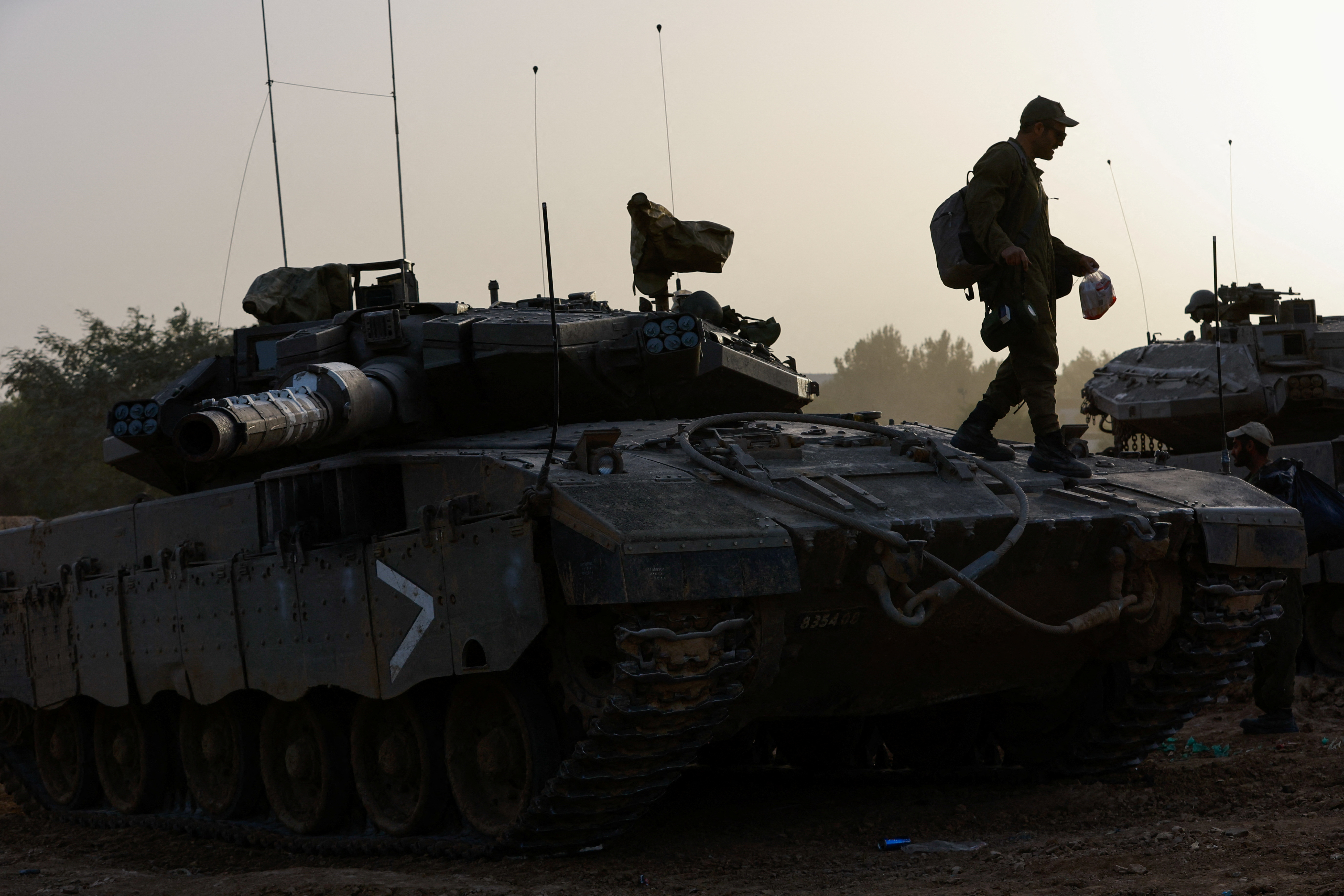 An Israeli soldier walks on a tank near the Israel-Gaza border during a temporary truce between Hamas and Israel