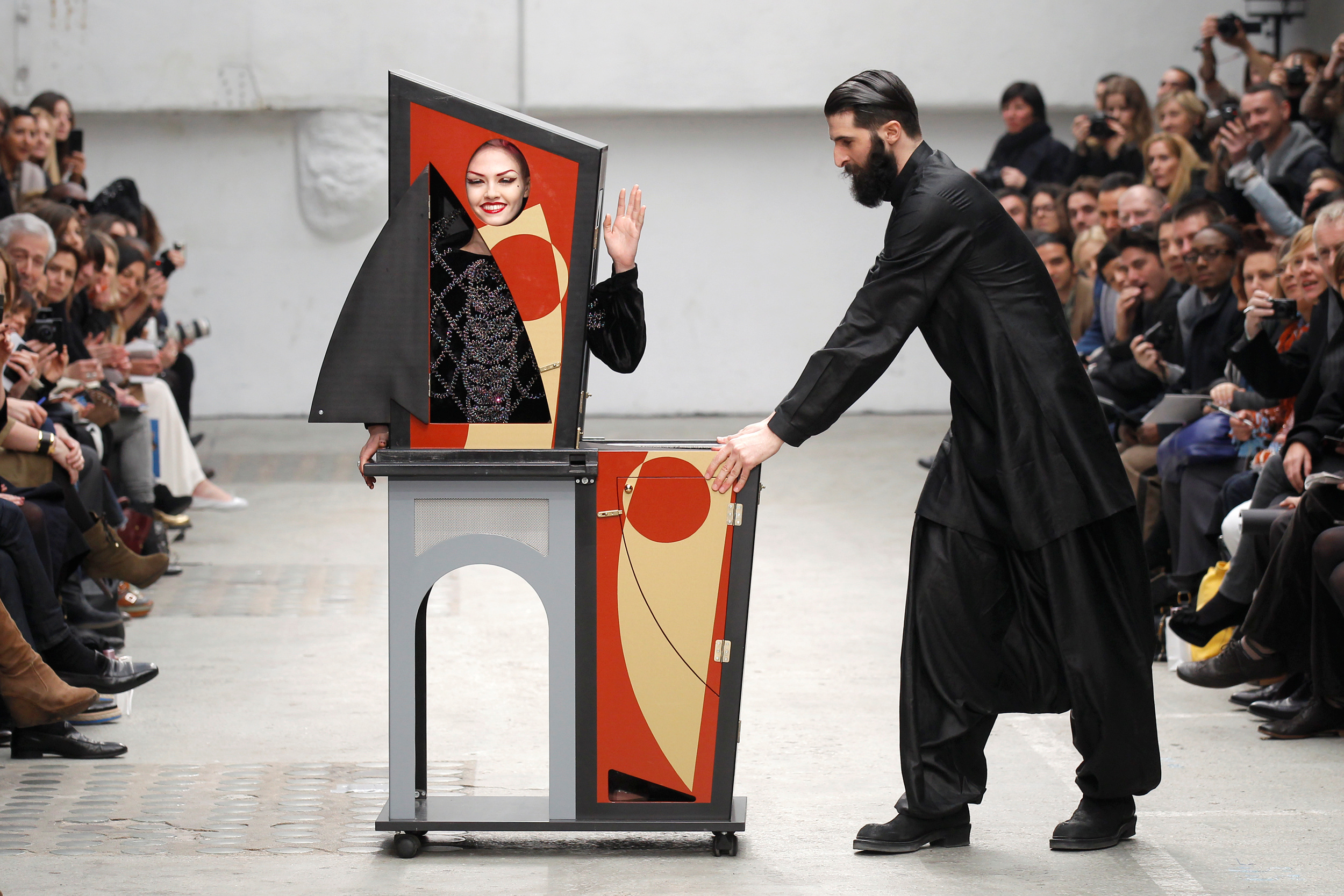 A magician performs with a model who presents a creation by Indian designer Manish Arora as part of his Fall-Winter 2011/2012 women's ready-to-wear fashion collection for French fashion house Guy Laroche during Paris Fashion Week