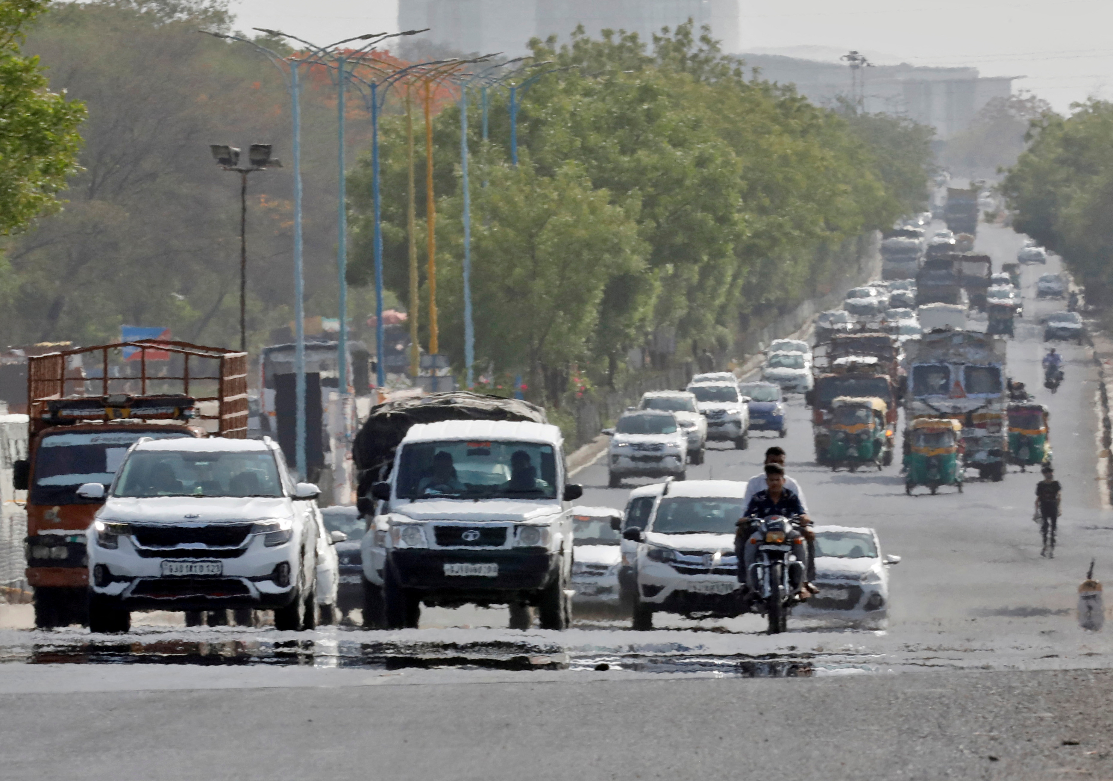 Traffic moves on a road in a heat haze during hot weather on the outskirts of Ahmedabad,