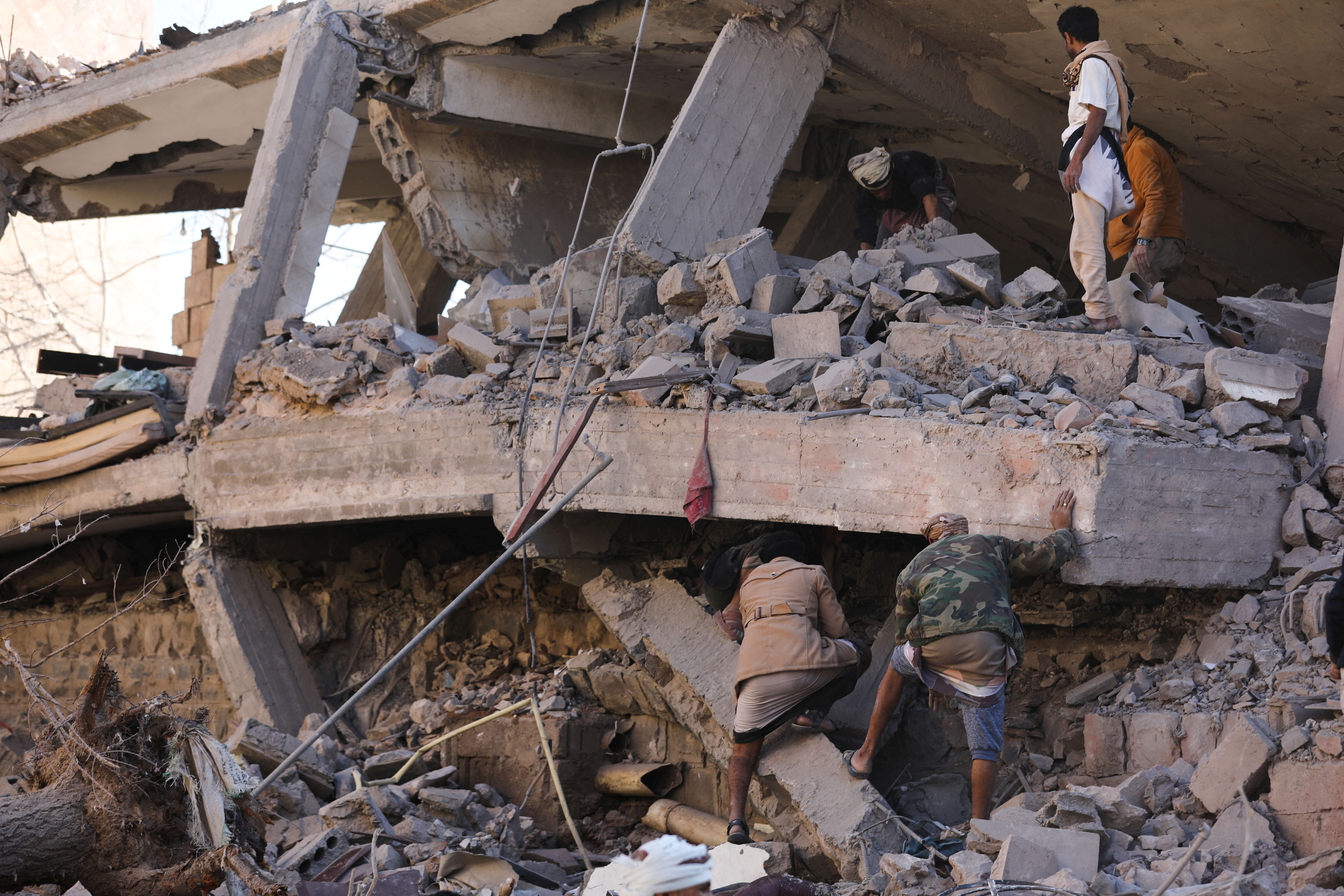 Rescuers search for survivors under the collapsed roof of a house hit by Saudi-led air strikes in Sanaa