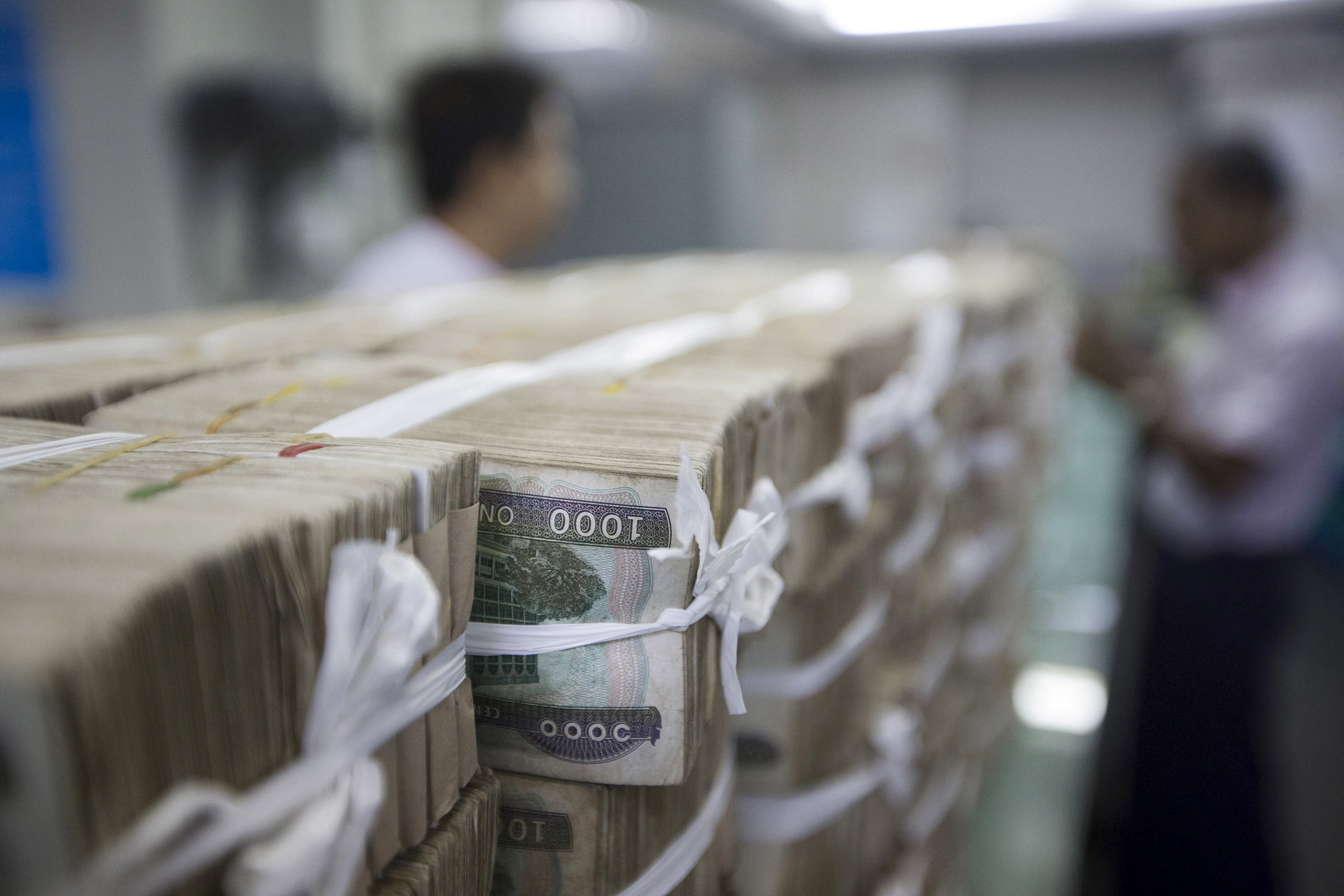 Stacks of Myanmar kyat are seen on the counter before a client collects them, at a bank in Yangon, Myanmar