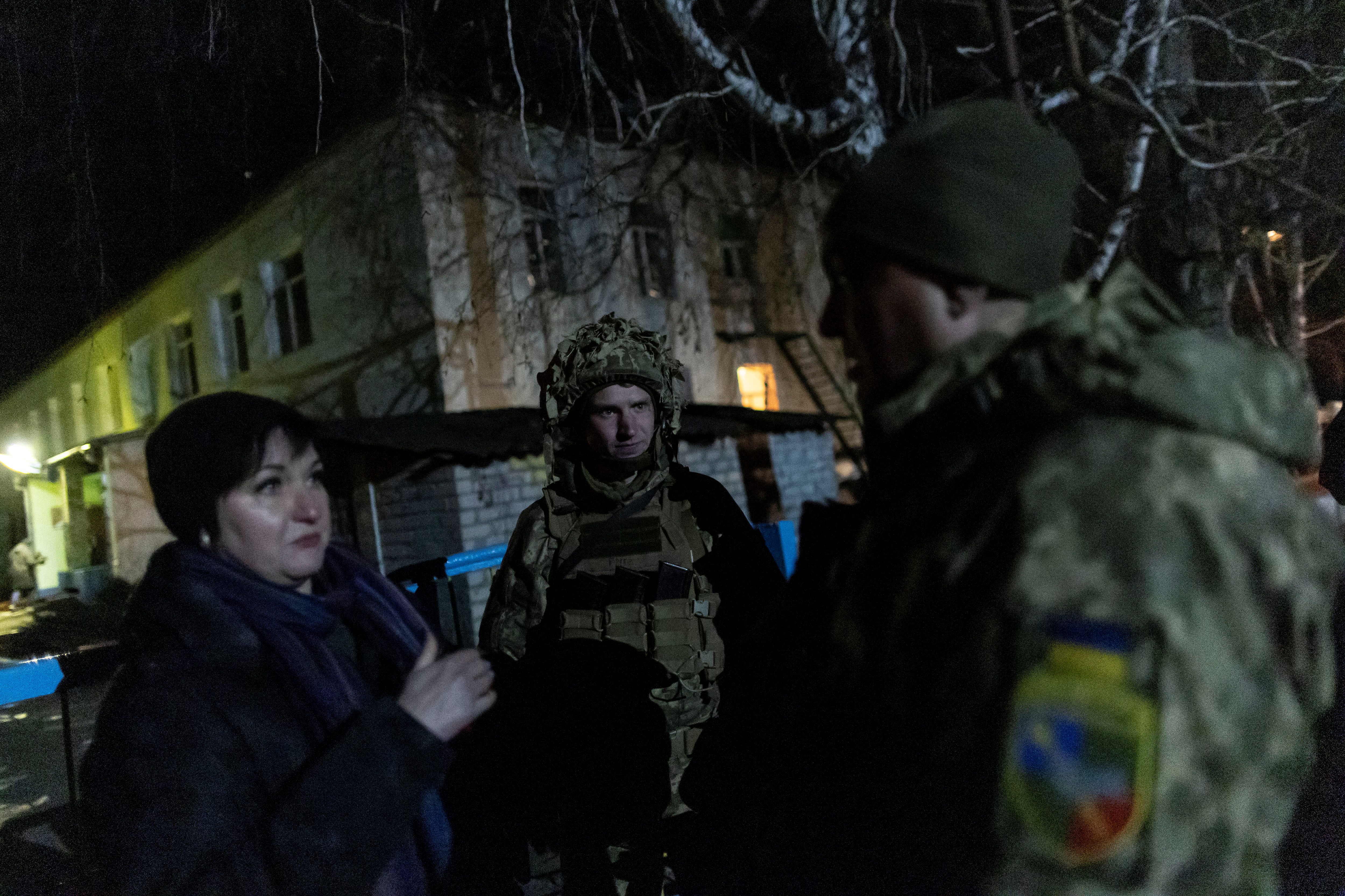 Service members of the Ukrainian armed forces talks with a local resident outside of a kindergarten, which, according to Ukraine's military officials, was damaged by shelling, in Stanytsia Luhanska, in the Luhansk region, Ukraine, February 17, 2022. REUTERS/Carlos Barria