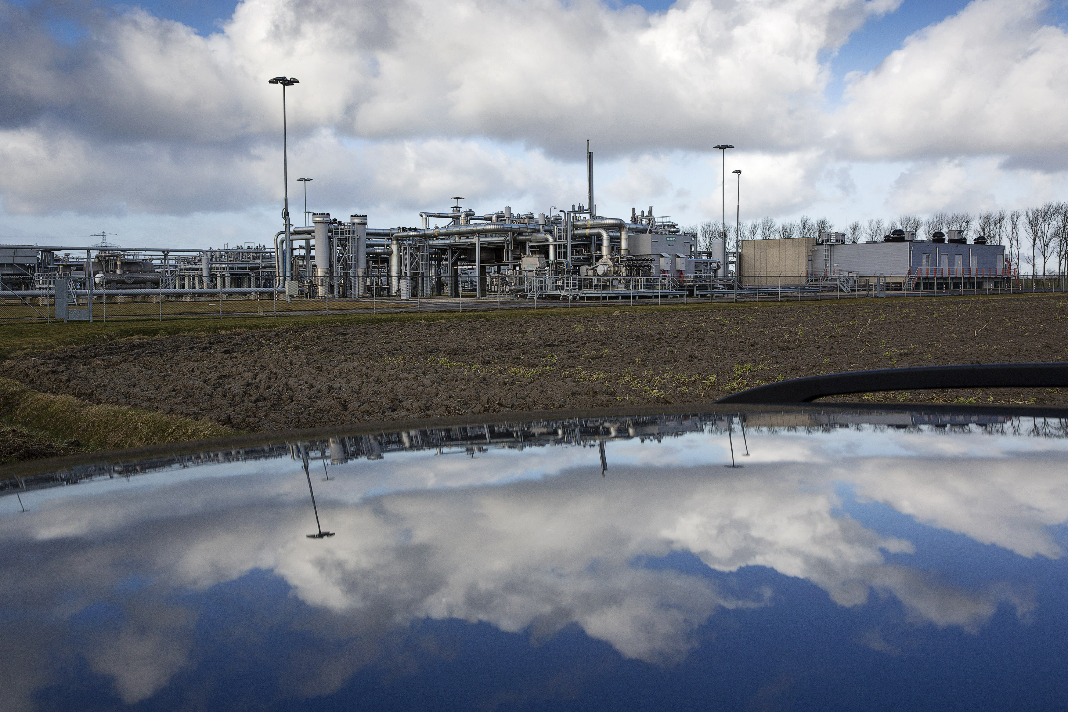 A view of a gas production plant is reflected in the roof of a car in 't Zand in Groningen