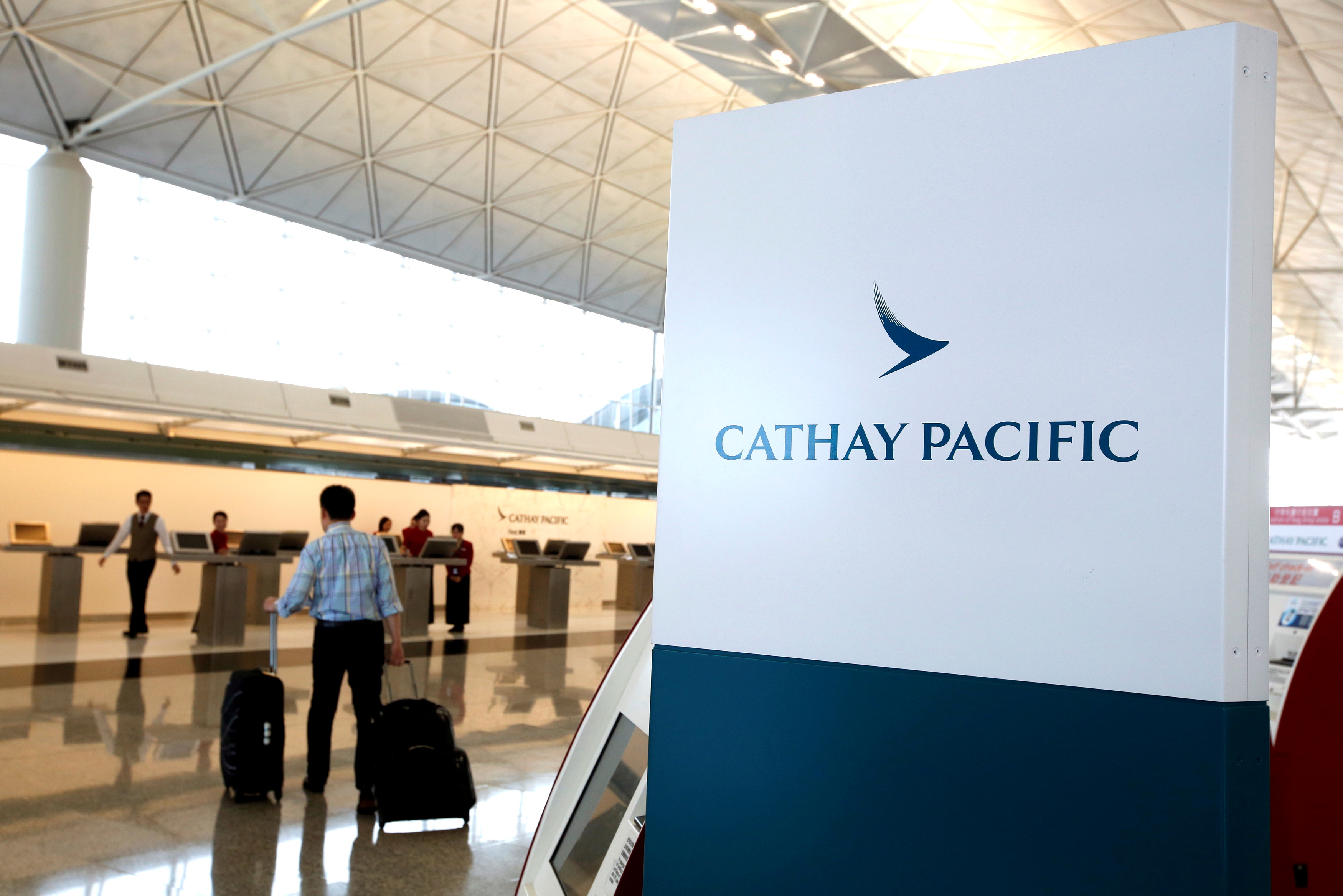 A passenger walks to the First Class counter of Cathay Pacific Airways at Hong Kong Airport in Hong Kong