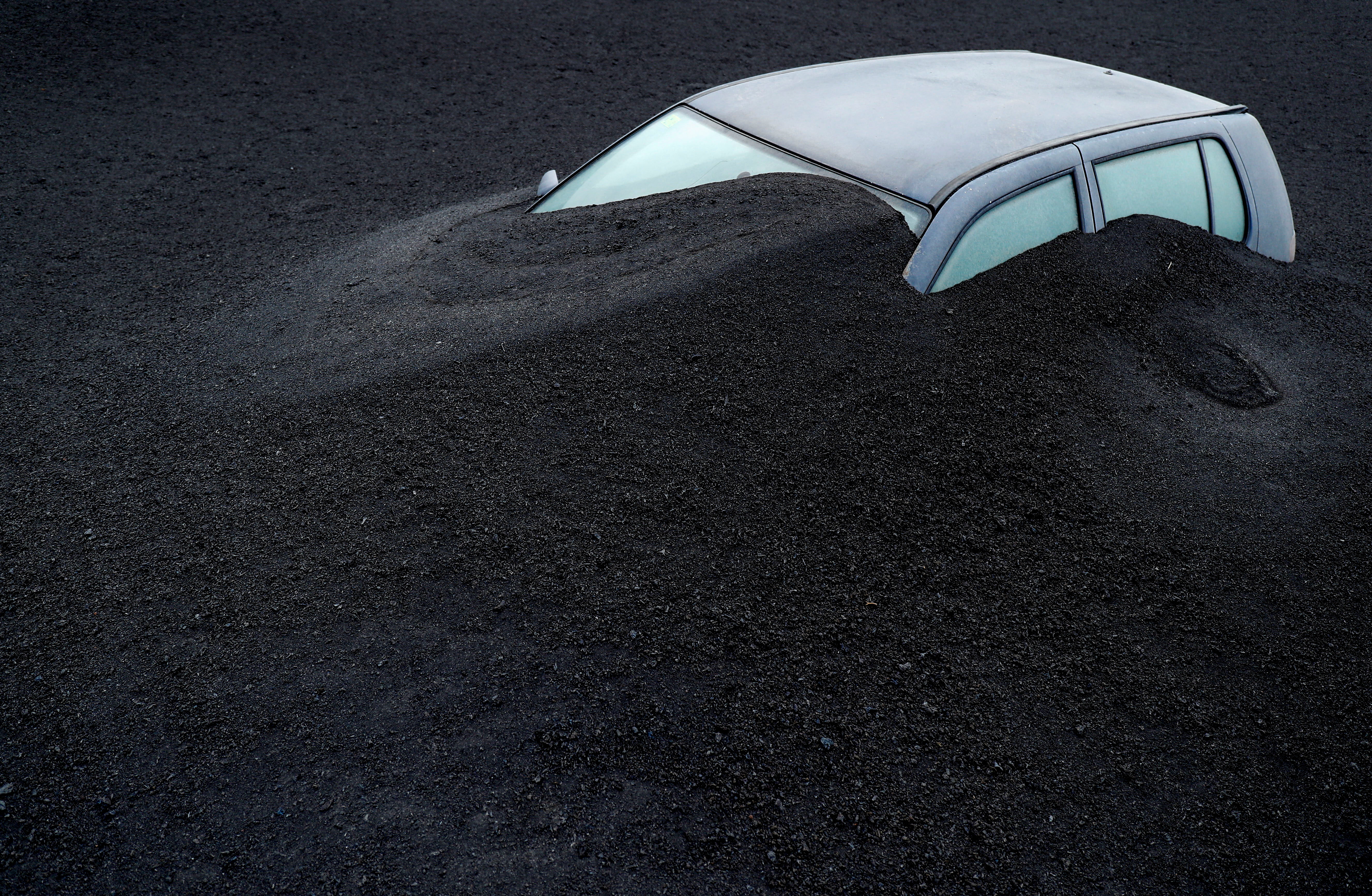 A vehicle is seen buried in the ash from the Cumbre Vieja volcano in Las Manchas neighbourhood