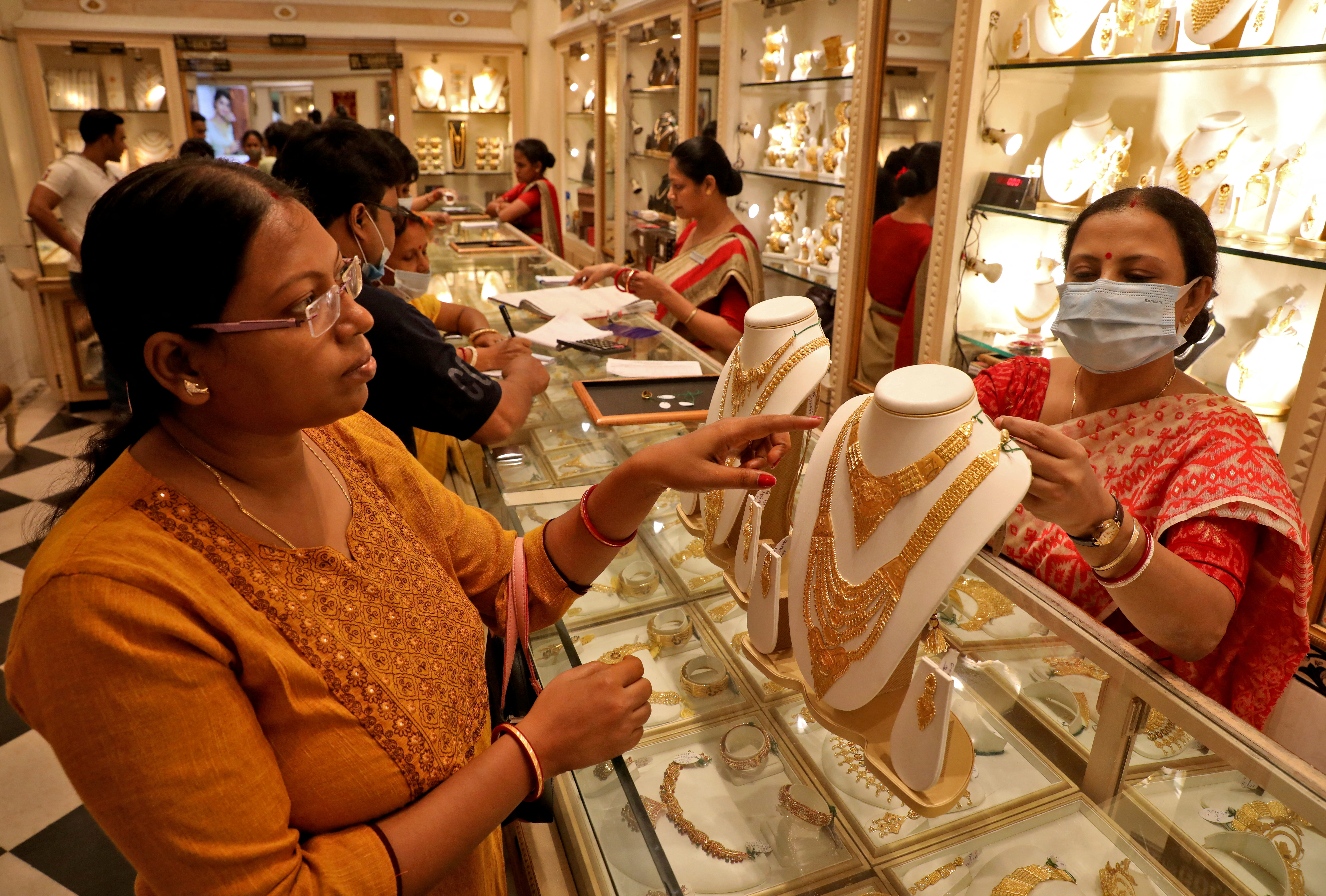 A customer checks a gold necklace before buying it at a jewellery showroom, in Kolkata