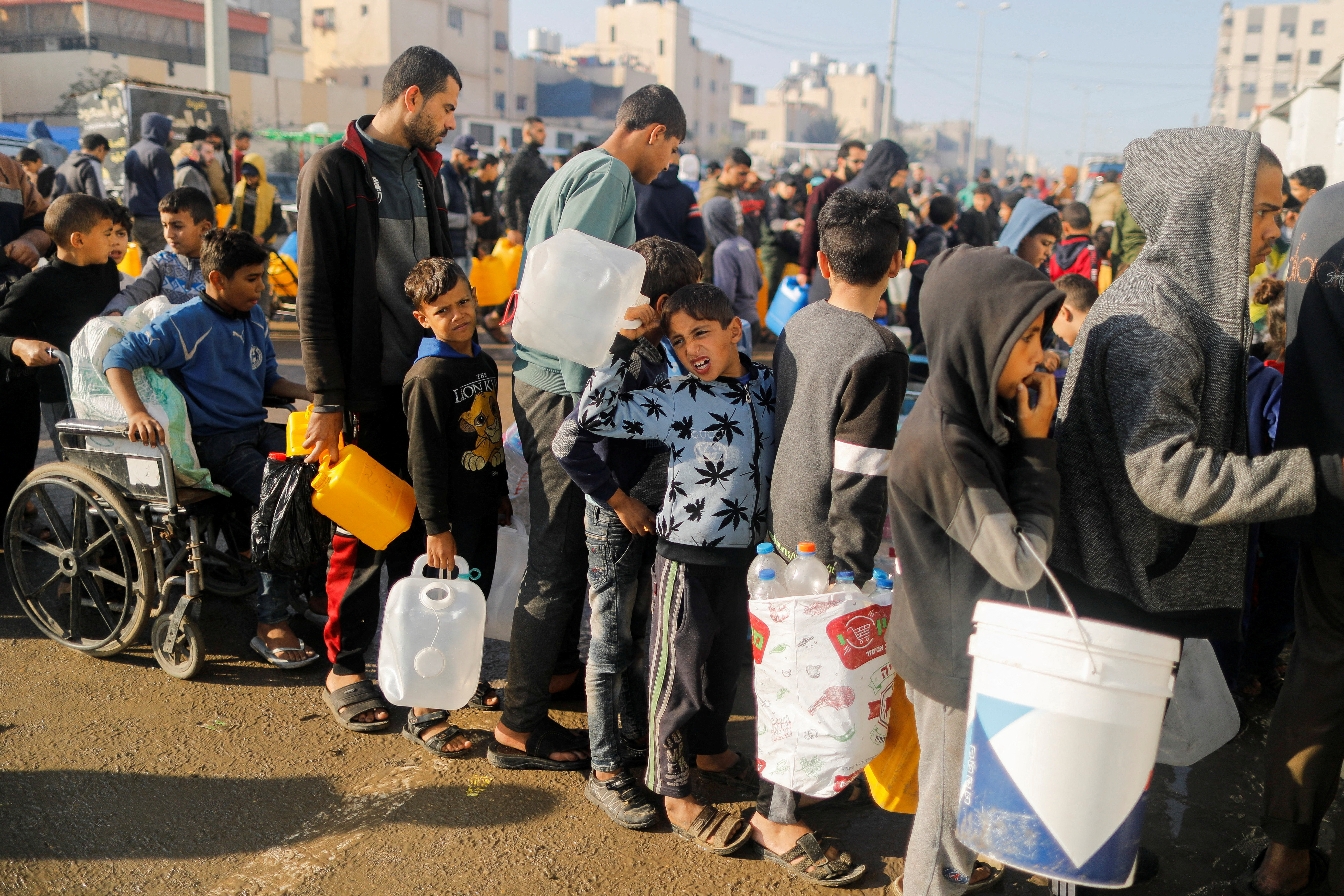 Palestinians queue as they wait to collect drinking water, amid shortages of drinking water, as the conflict between Israel and Hamas continues, in Rafah