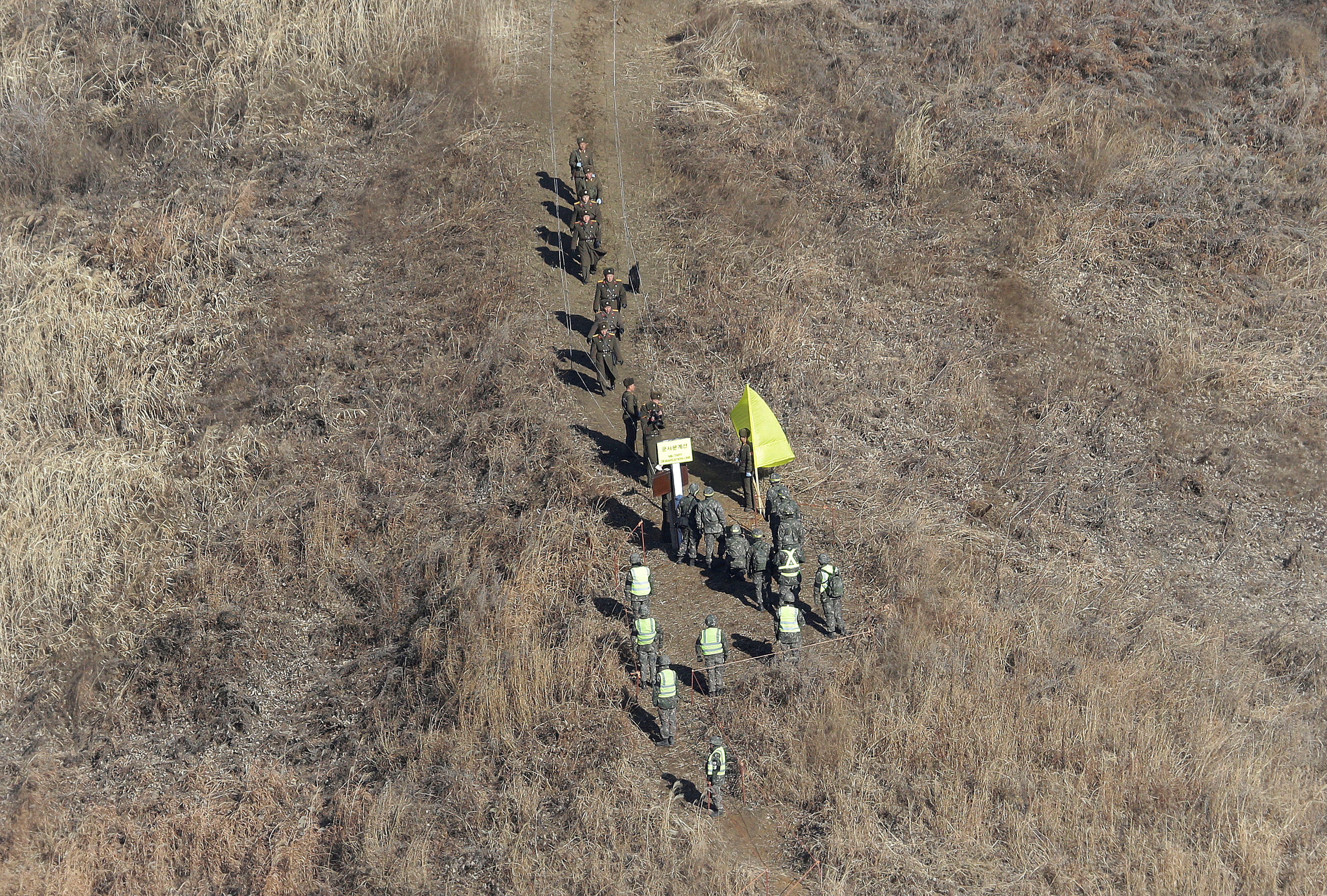 North Korean army soldiers head to cross the Military Demarcation Line inside the Demilitarized Zone (DMZ) to inspect the dismantled South Korean guard post in Cheorwon