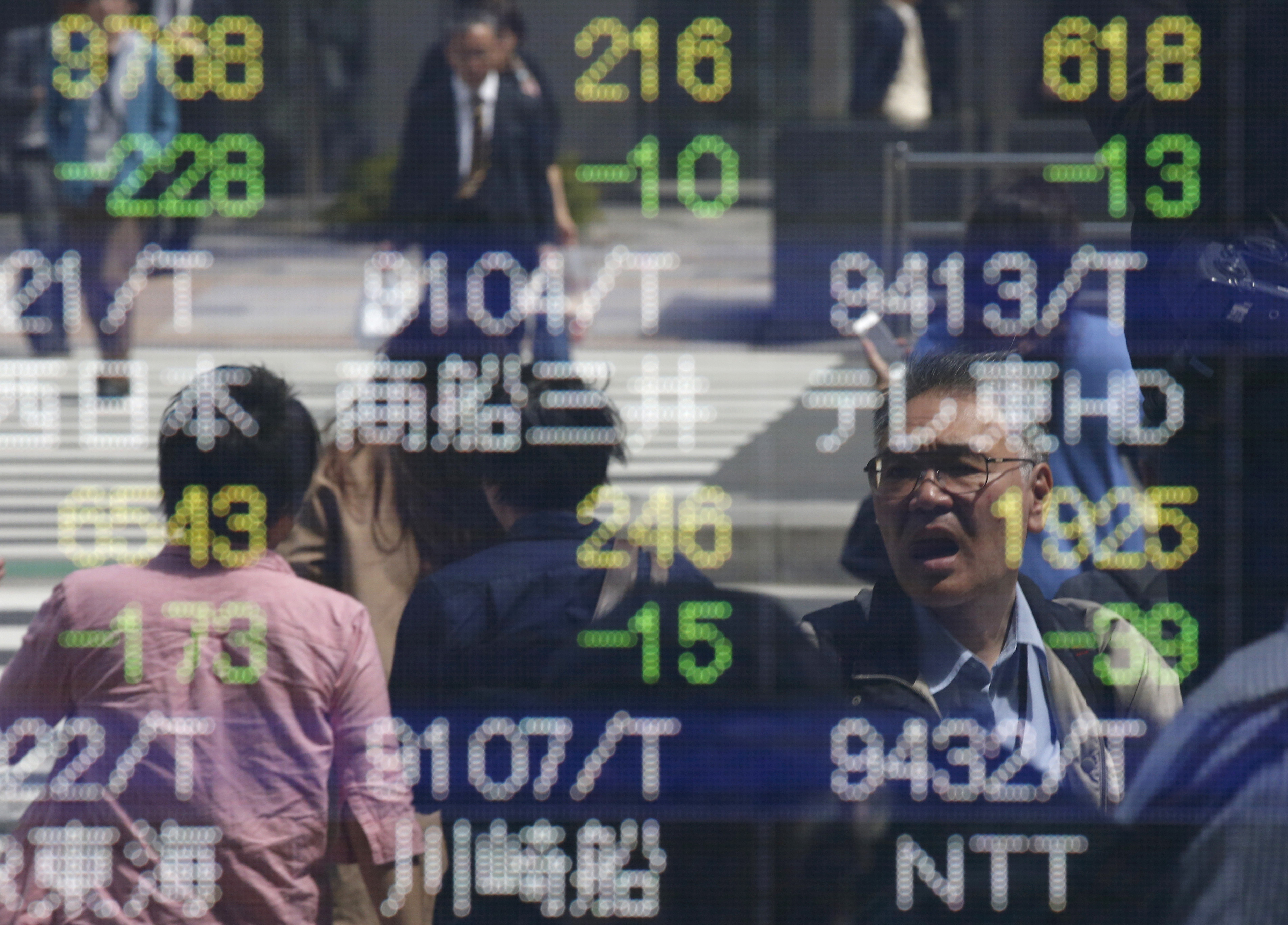 People are reflected in a stock quotation board outside a brokerage in Tokyo, Japan, April 18, 2016.  REUTERS/Toru Hanai