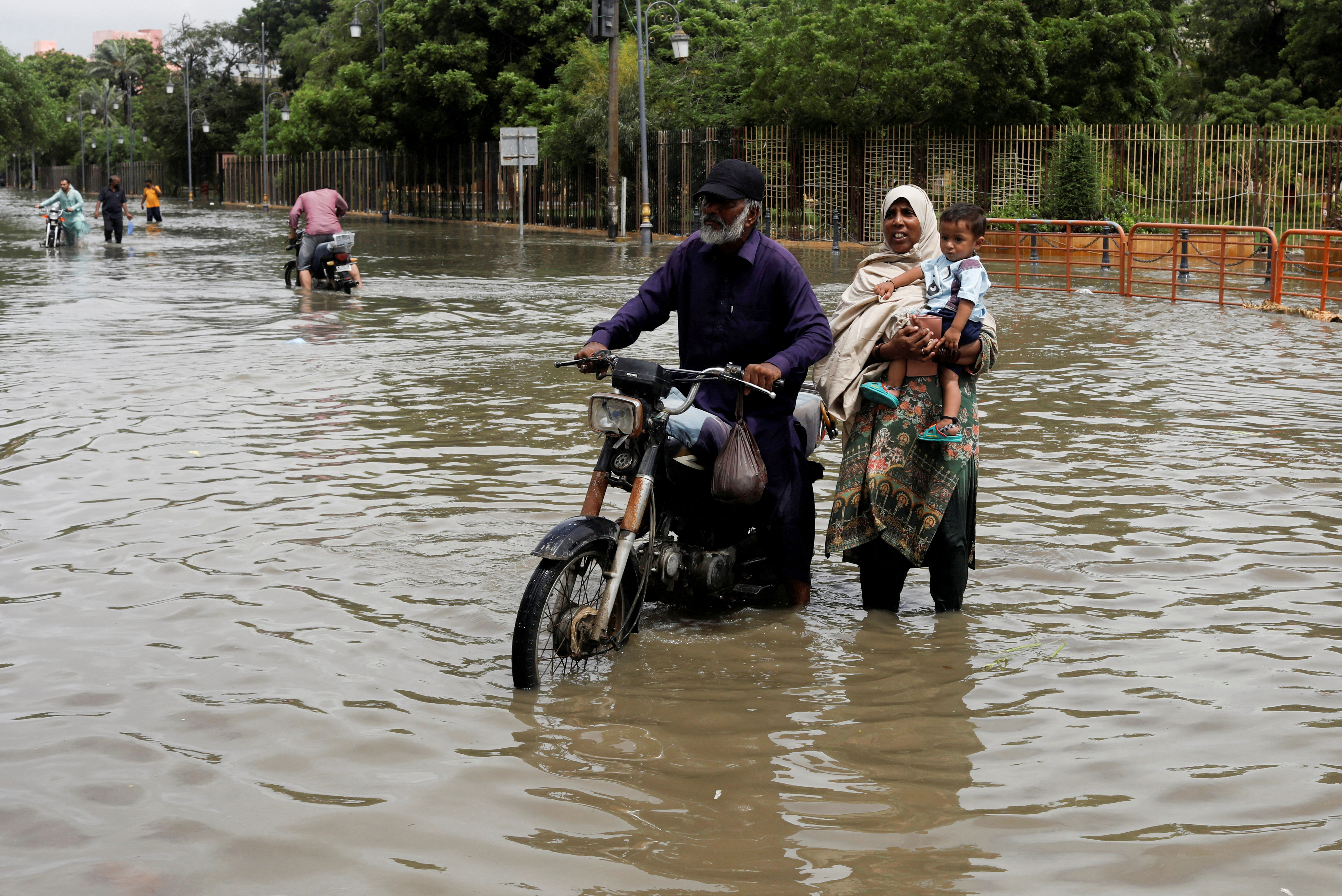 A family wade through a flooded street during the monsoon season in Karachi