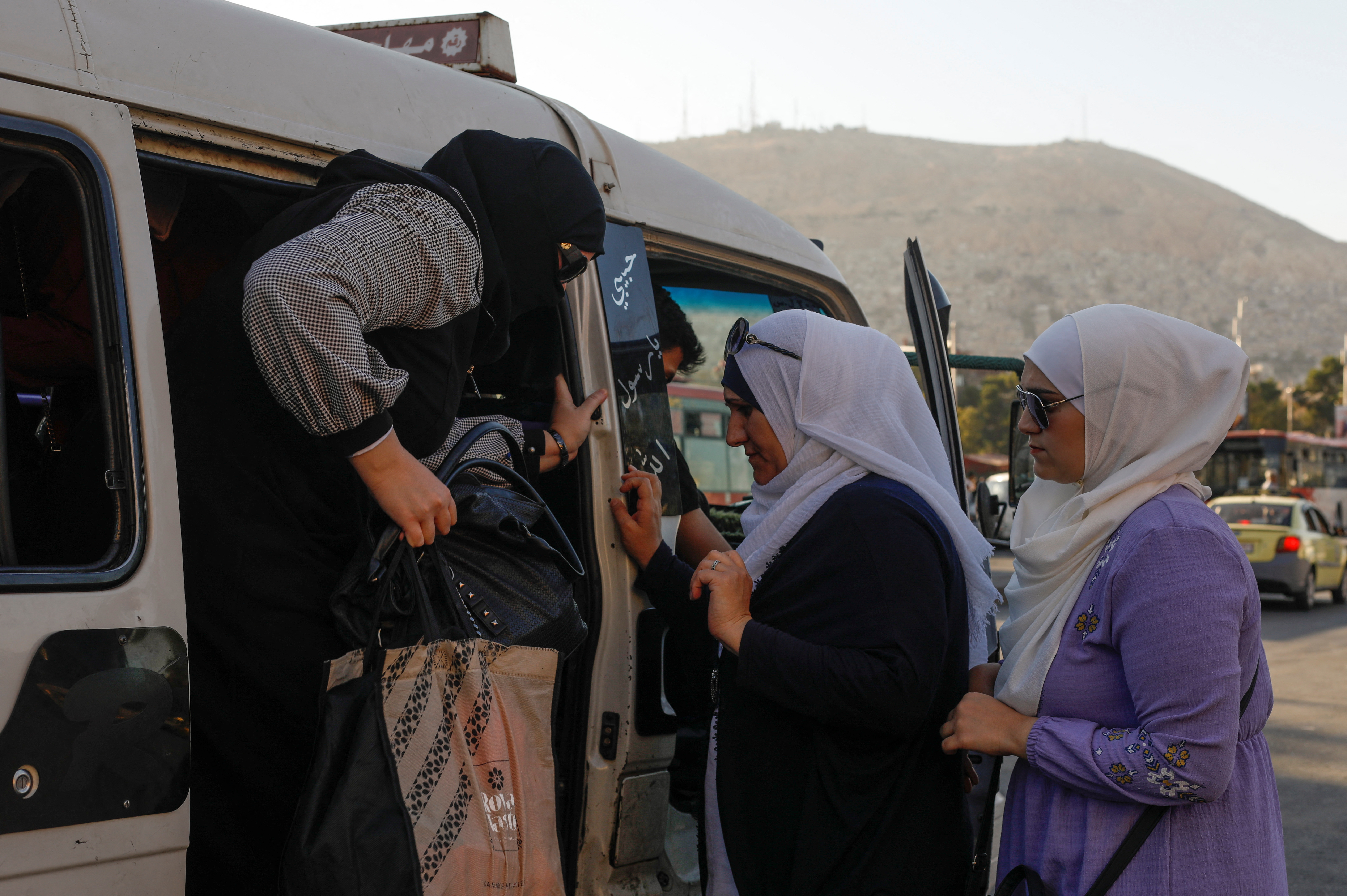 Women board a public minibus in Damascus
