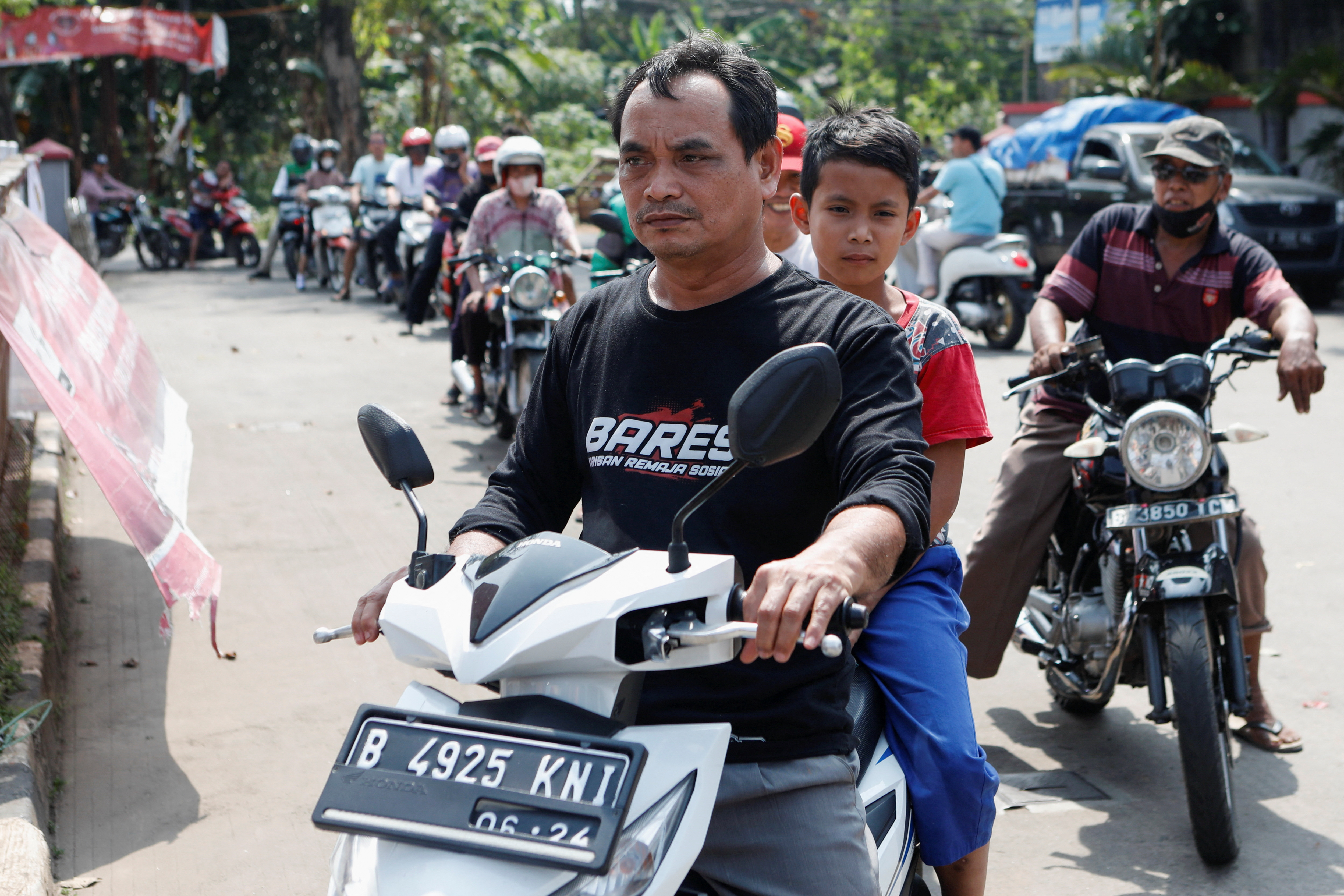 Motorcycle drivers wait in line to buy subsidised fuel at a petrol station of the state-owned company Pertamina after the announcement of a fuel price hike, in Bekasi
