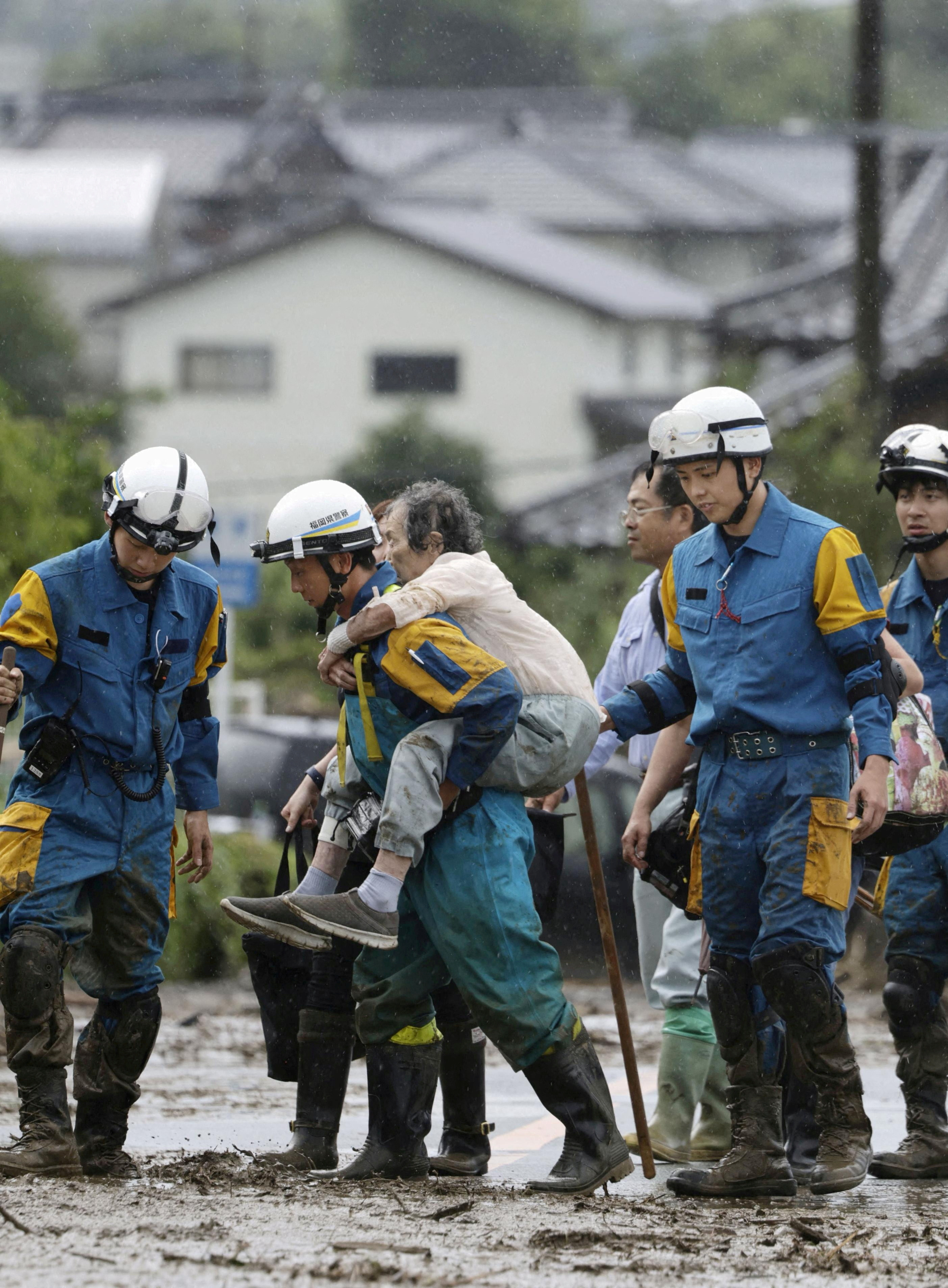 A police officer carries a person who is evacuated from a site of a landslide after the heavy rain in Kurume