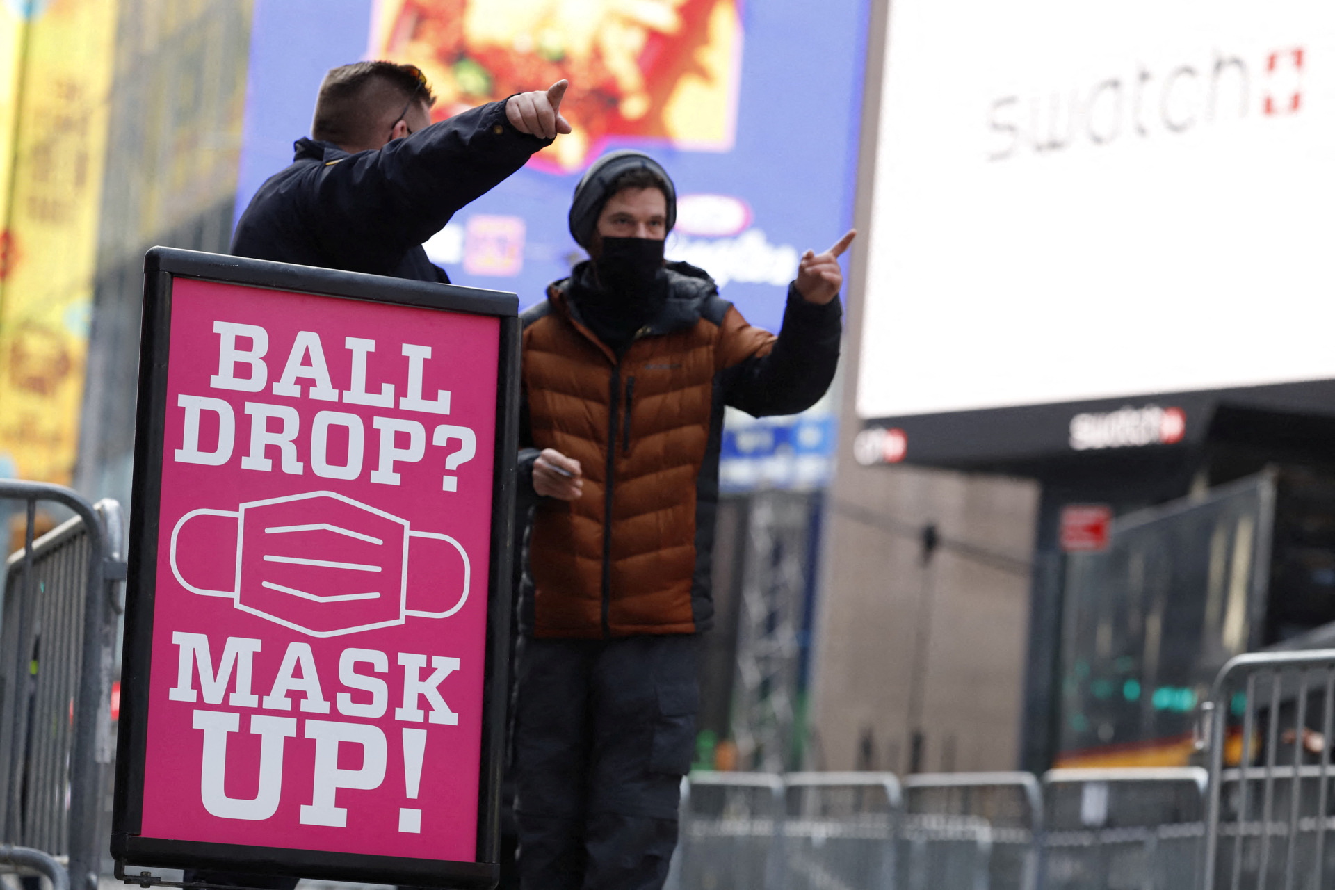 An officer from the New York City Police Department (NYPD) helps a person with directions while standing next to a signage encouraging people to wear masks ahead of New Year's Eve celebrations at Times Square as the Omicron variant continues to spread in the Manhattan borough of New York City, U.S., December 31, 2021. REUTERS/Stefan Jeremiah