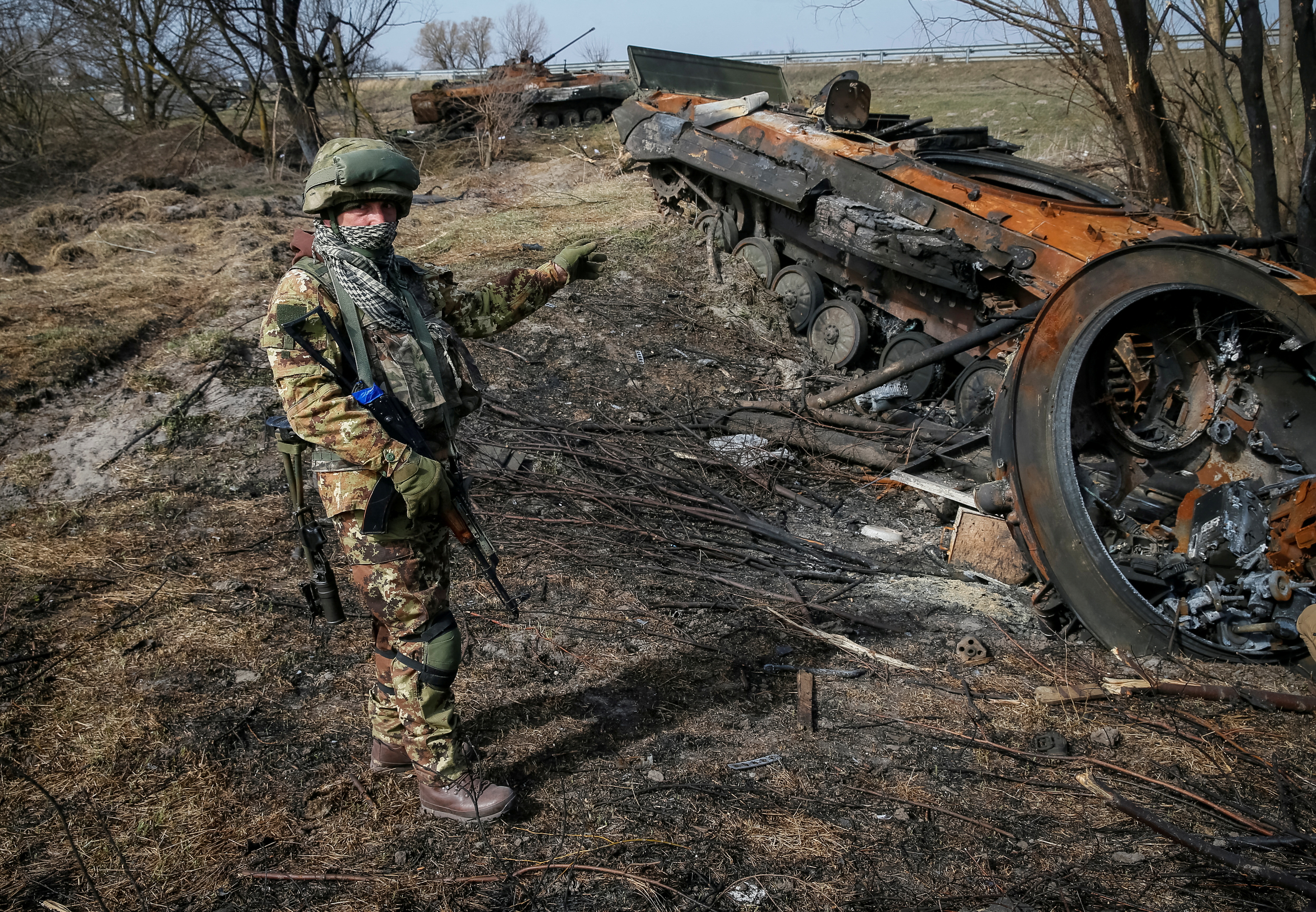 A Ukrainian serviceman stands near the wreck of a Russian Armoured Personnel Carrier on the front line in the Kyiv region