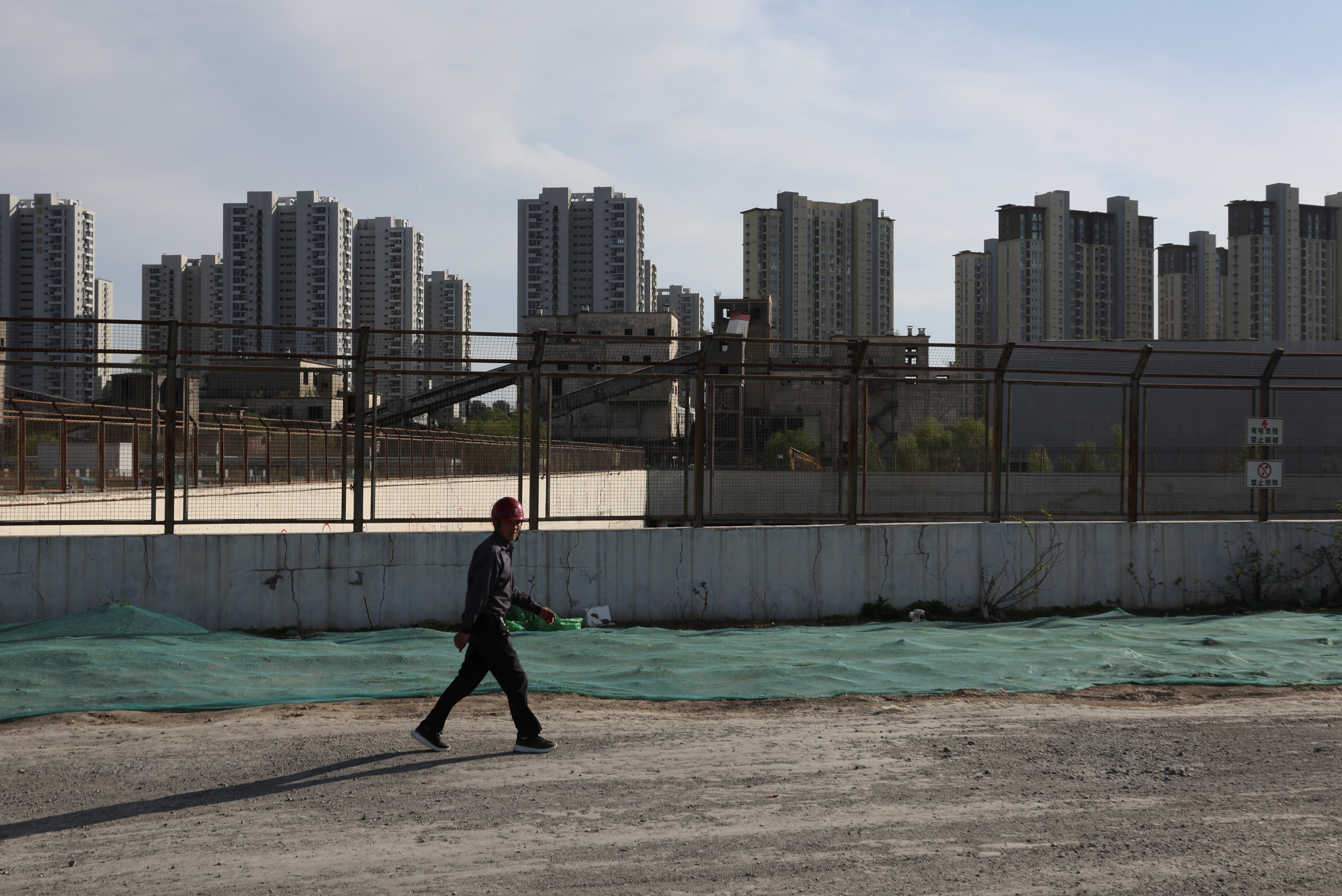 Worker walks past a construction site near residential buildings in Beijing