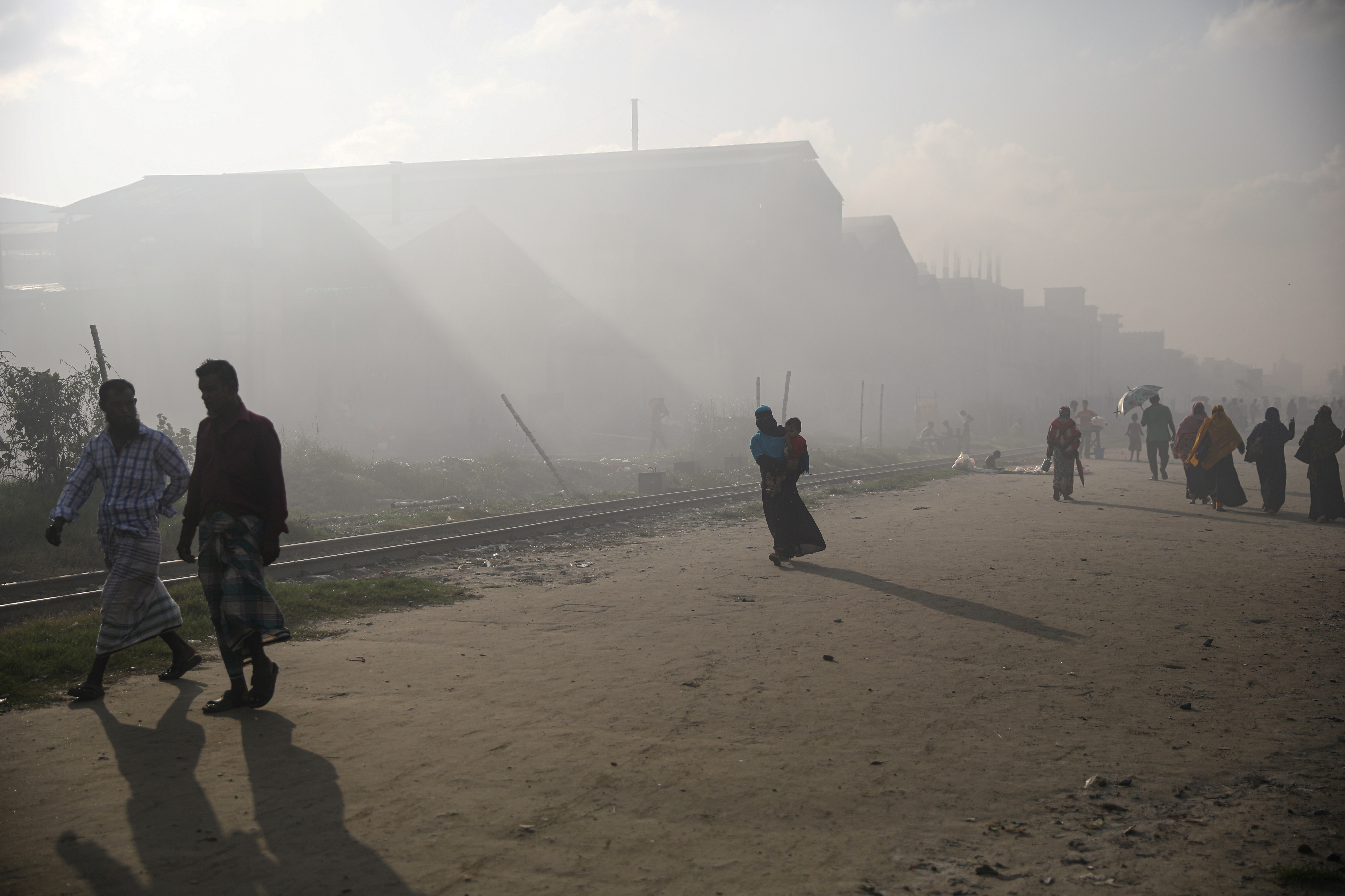 People walk through a polluted industrial area in Dhaka