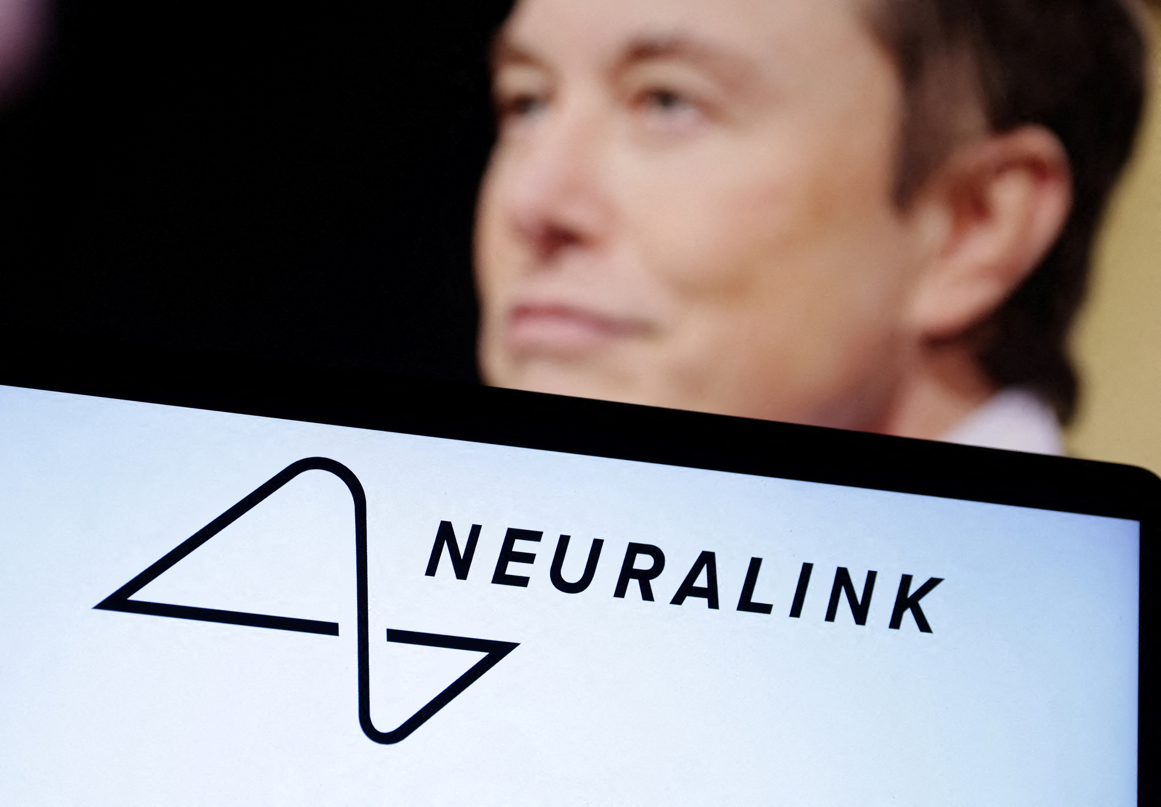 Η εικόνα δείχνει το λογότυπο Neuralink και τη φωτογραφία του Elon Musk