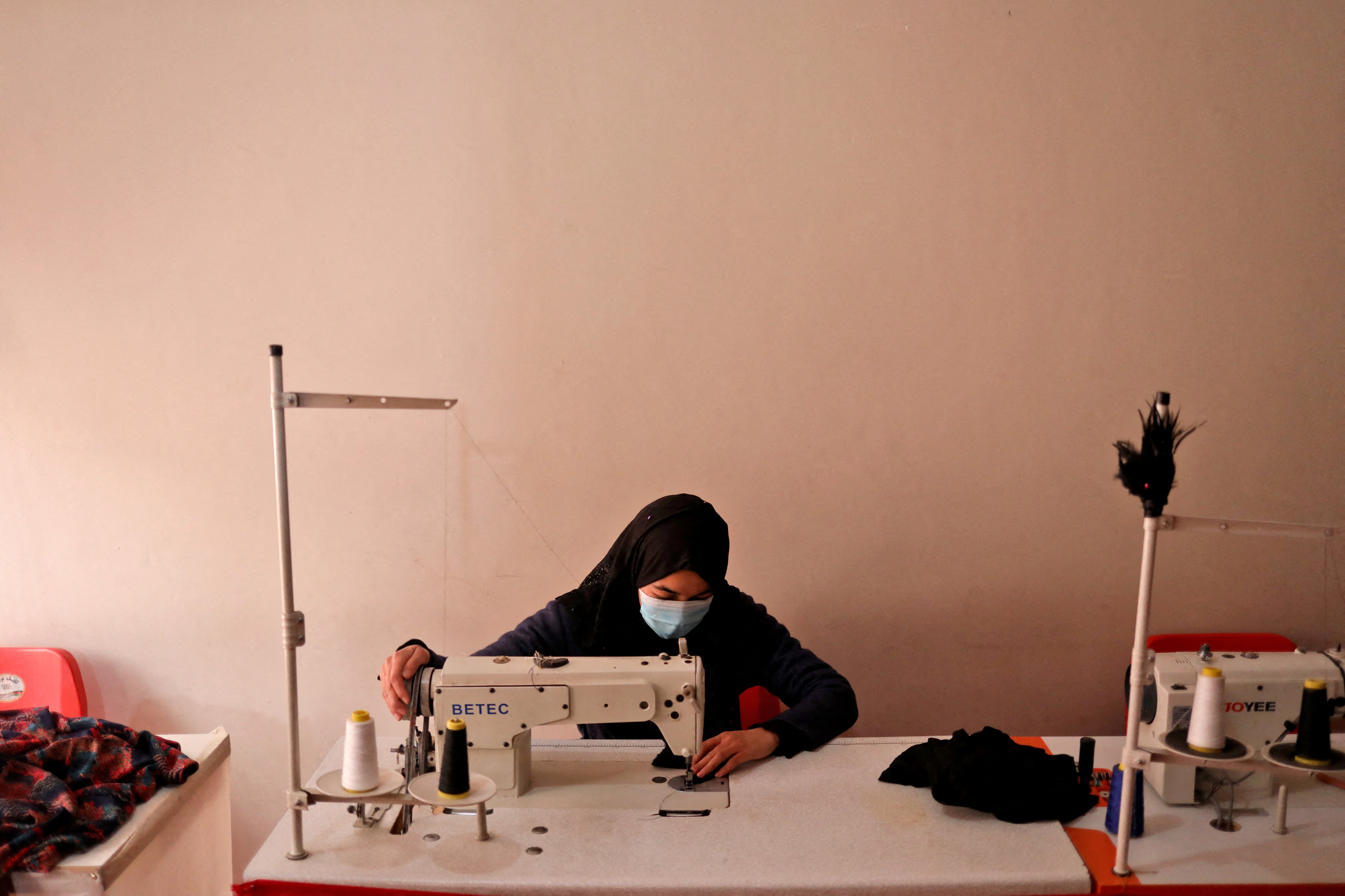An Afghan woman uses a sewing machine to sew garments at a sewing workshop in Kabul