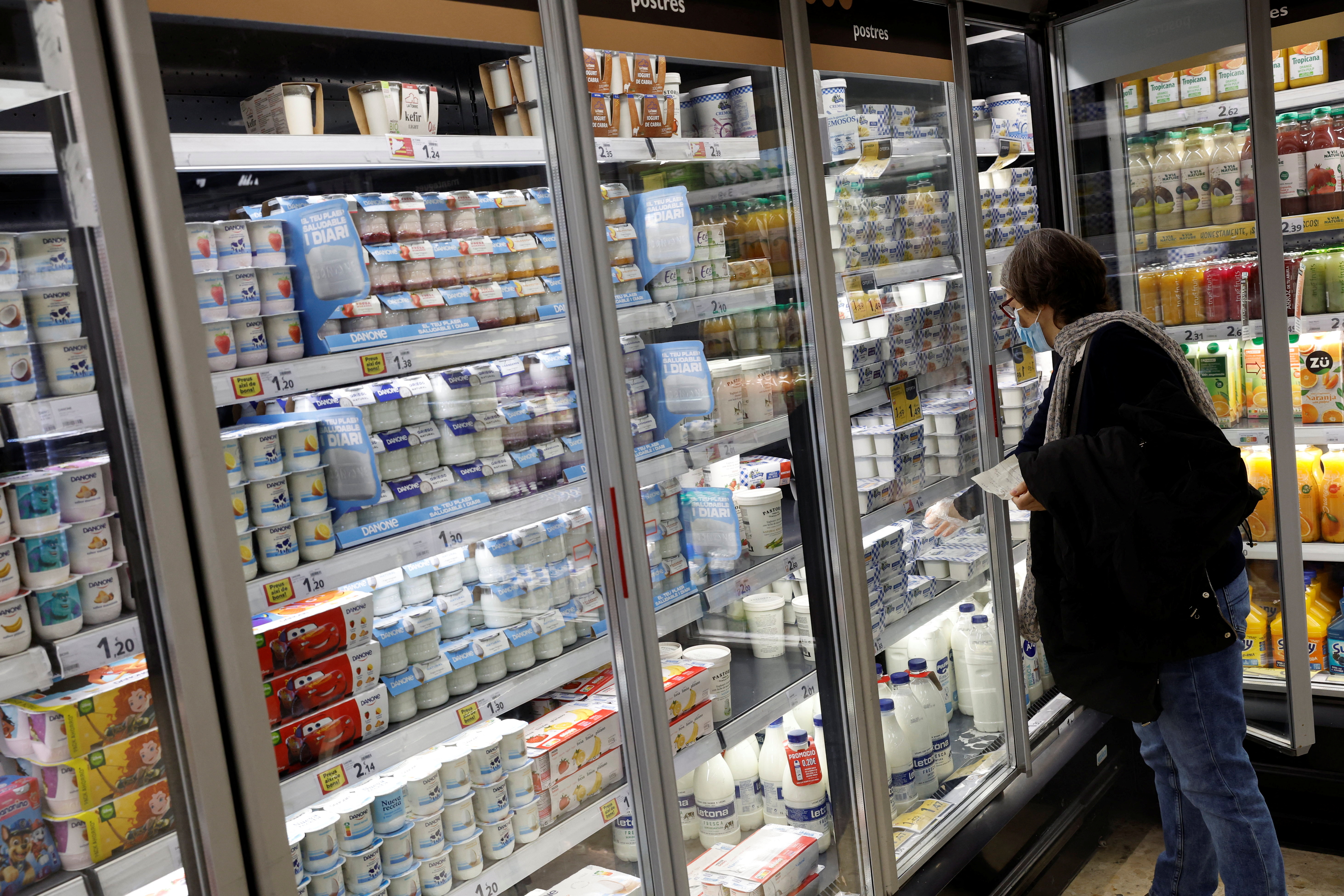 A woman takes some yogurts from a fridge in a Caprabo supermarket in Barcelona