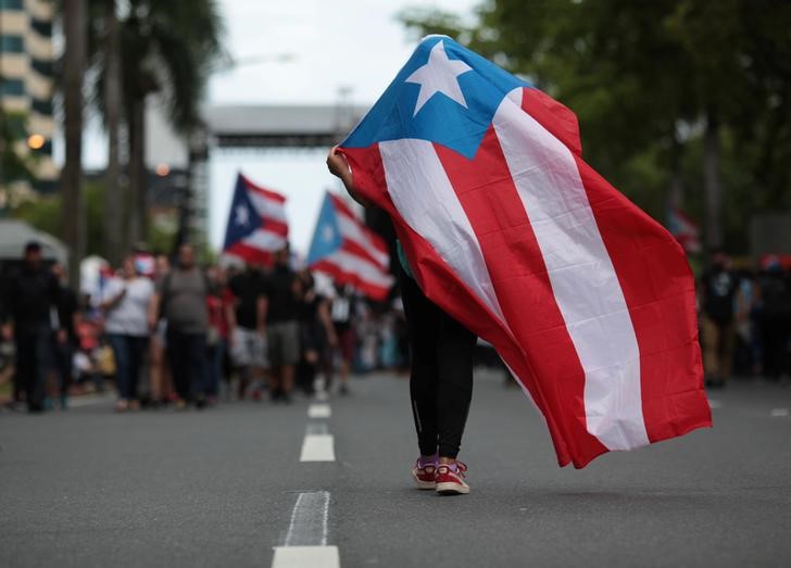 A person carries a Puerto Rican national flag during a protest against the government's austerity measures as Puerto Rico faces a deadline on Monday to restructure its $70 billion debt load or open itself up to lawsuits from creditors, in San Juan