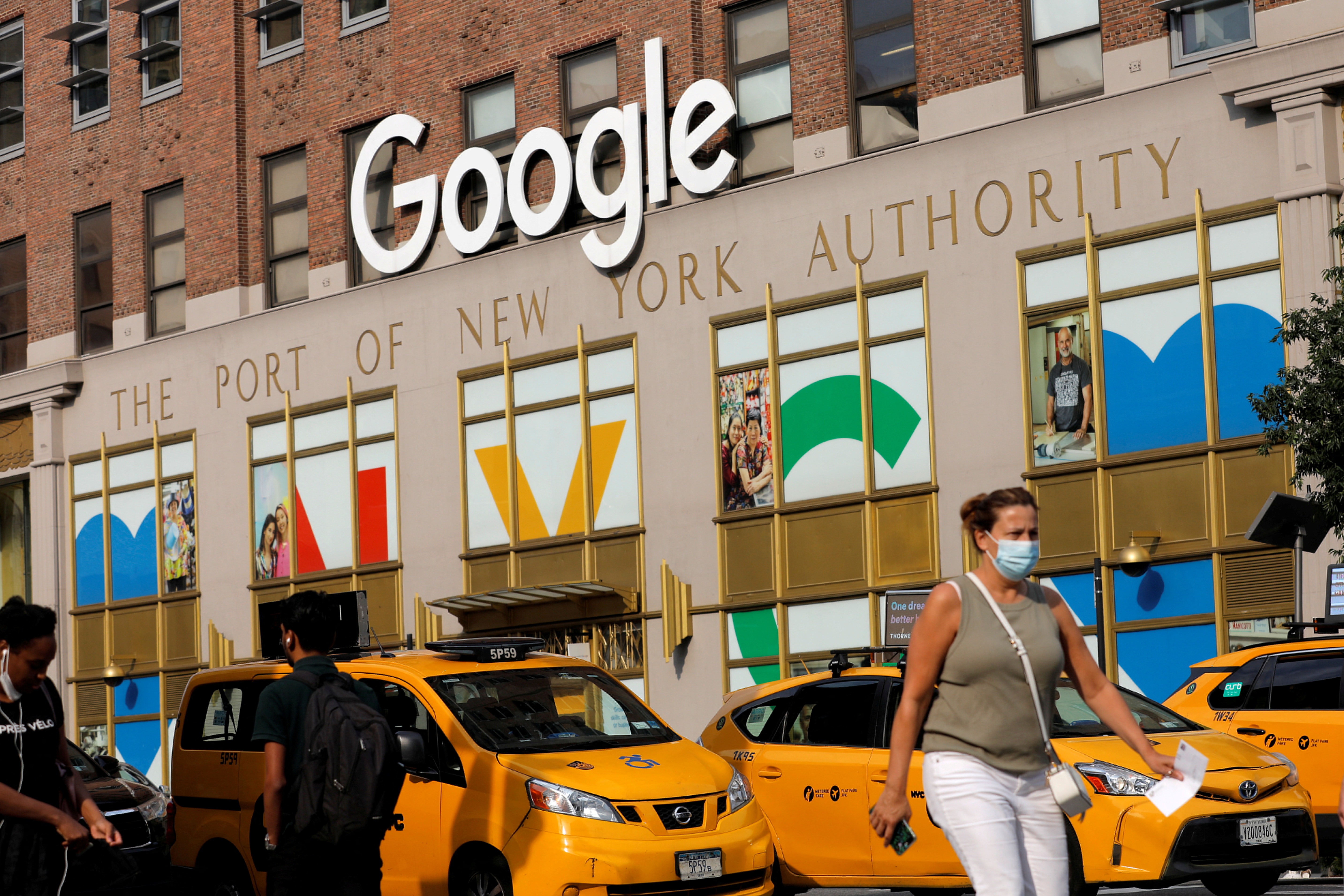 A person in a mask walks by the New York Google offices in New York City