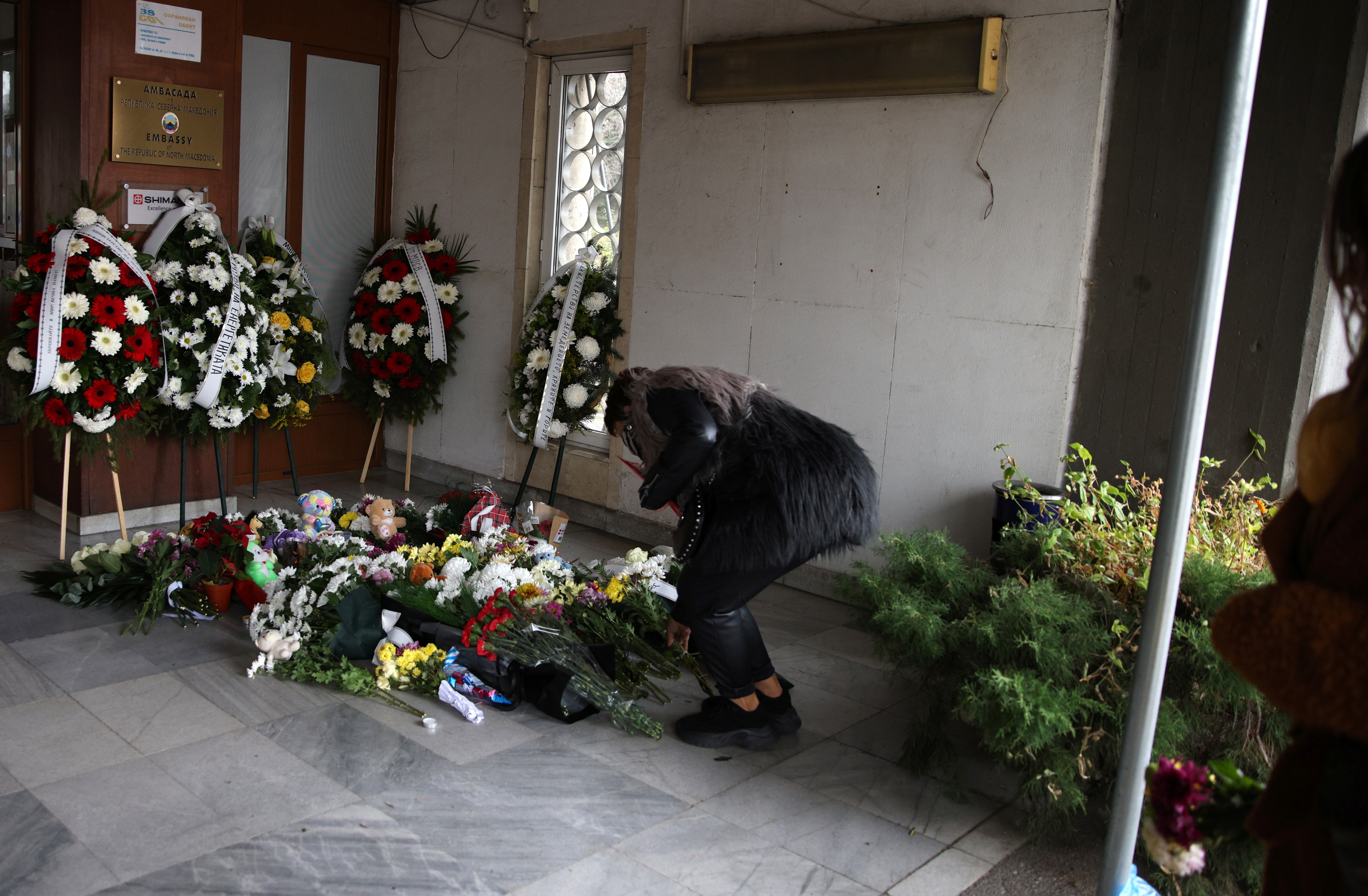 A woman lays flowers at a makeshift memorial for the victims of Tuesday's bus accident, in front of the embassy of North Macedonia, Sofia, Bulgaria, November 24, 2021. REUTERS/Stoyan Nenov