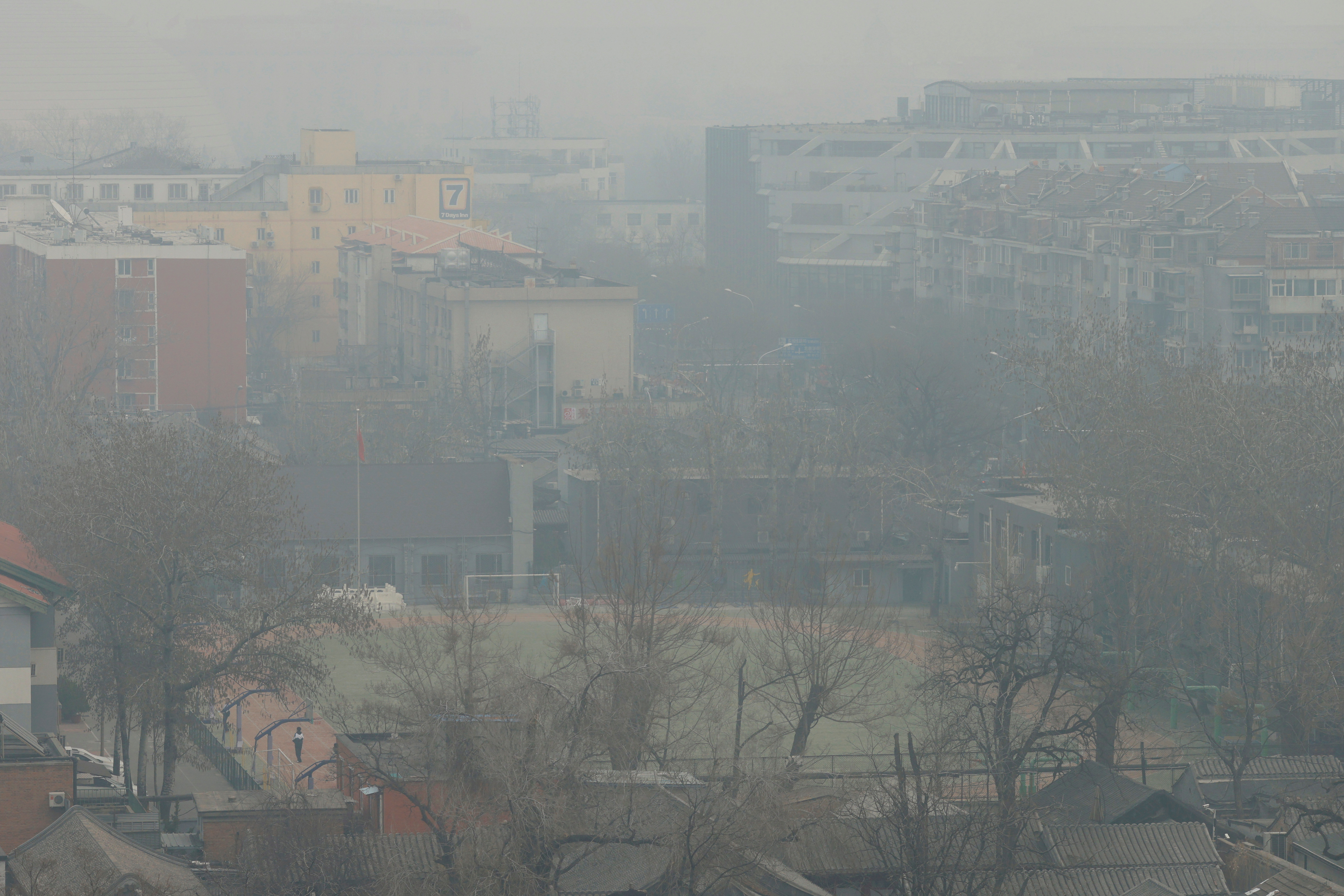 Student stands on a sports field shrouded in smog on a polluted day in Beijing