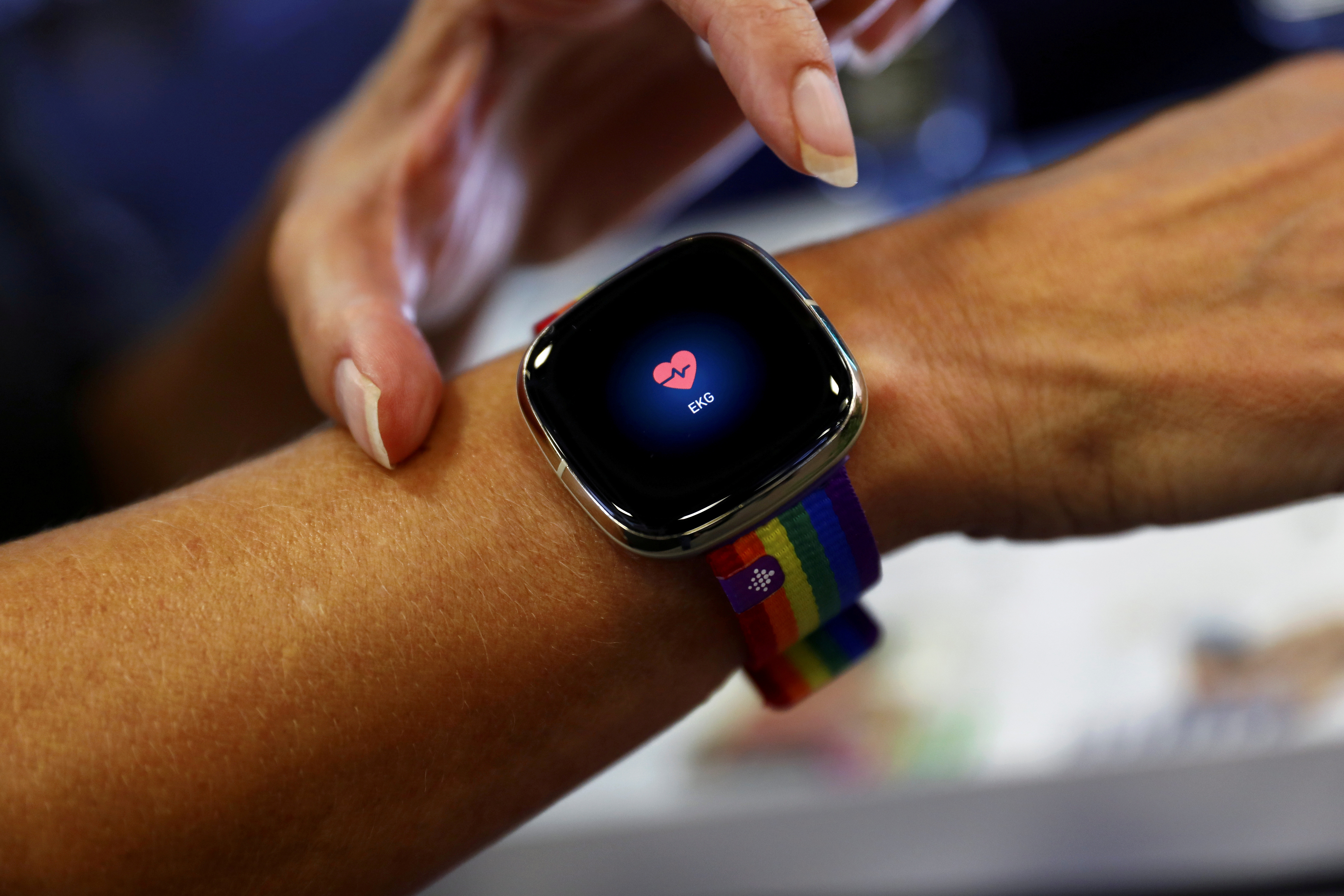 An employee uses an electrocardiogram function on a Fitbit smartwatch at the IFA consumer technology fair, in Berlin