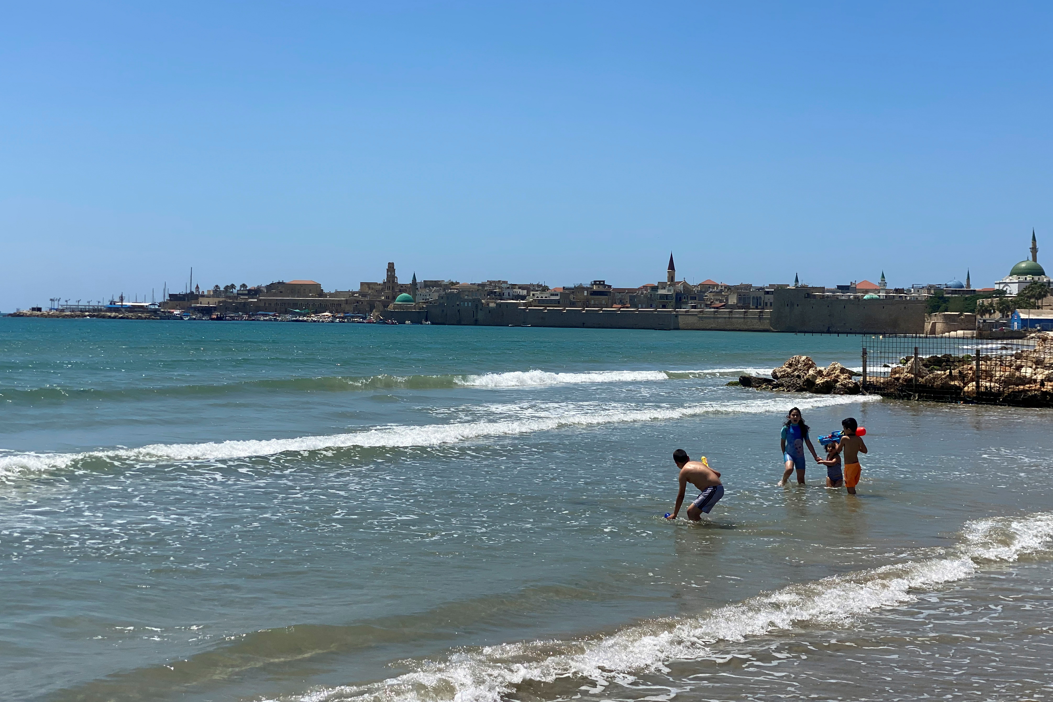Children play in the Mediterranean Sea in the Arab-Jewish mixed coastal city of Acre