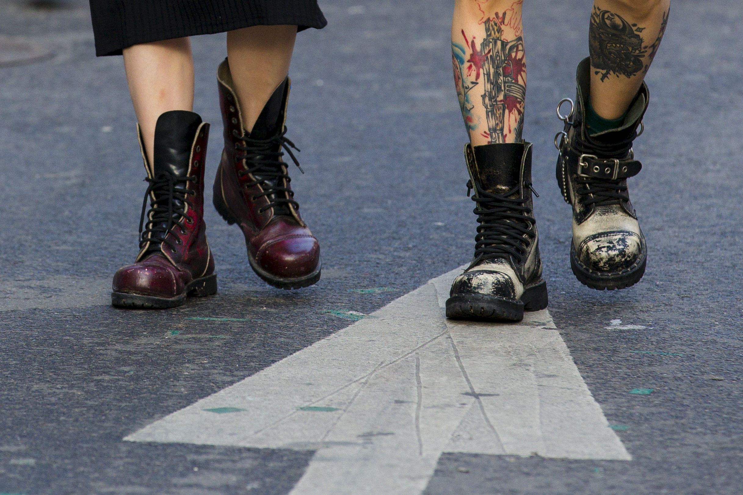 Tattooed man and woman wear heavy boots as they walk in trendy shopping district of Hongdae in Seoul