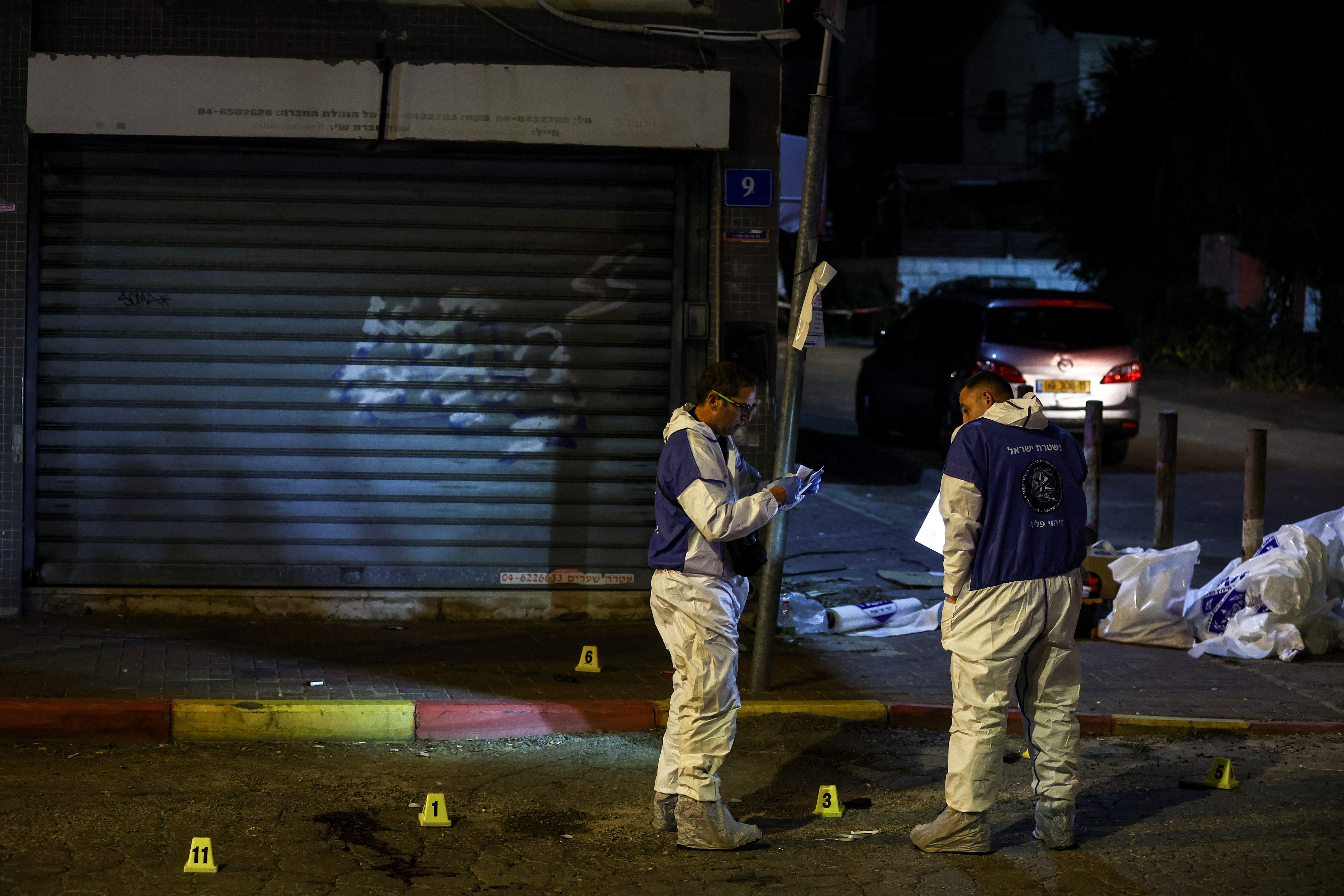 Israeli police forensics experts work at the scene of an attack in which people were killed by gunmen on a main street in Hadera, Israel