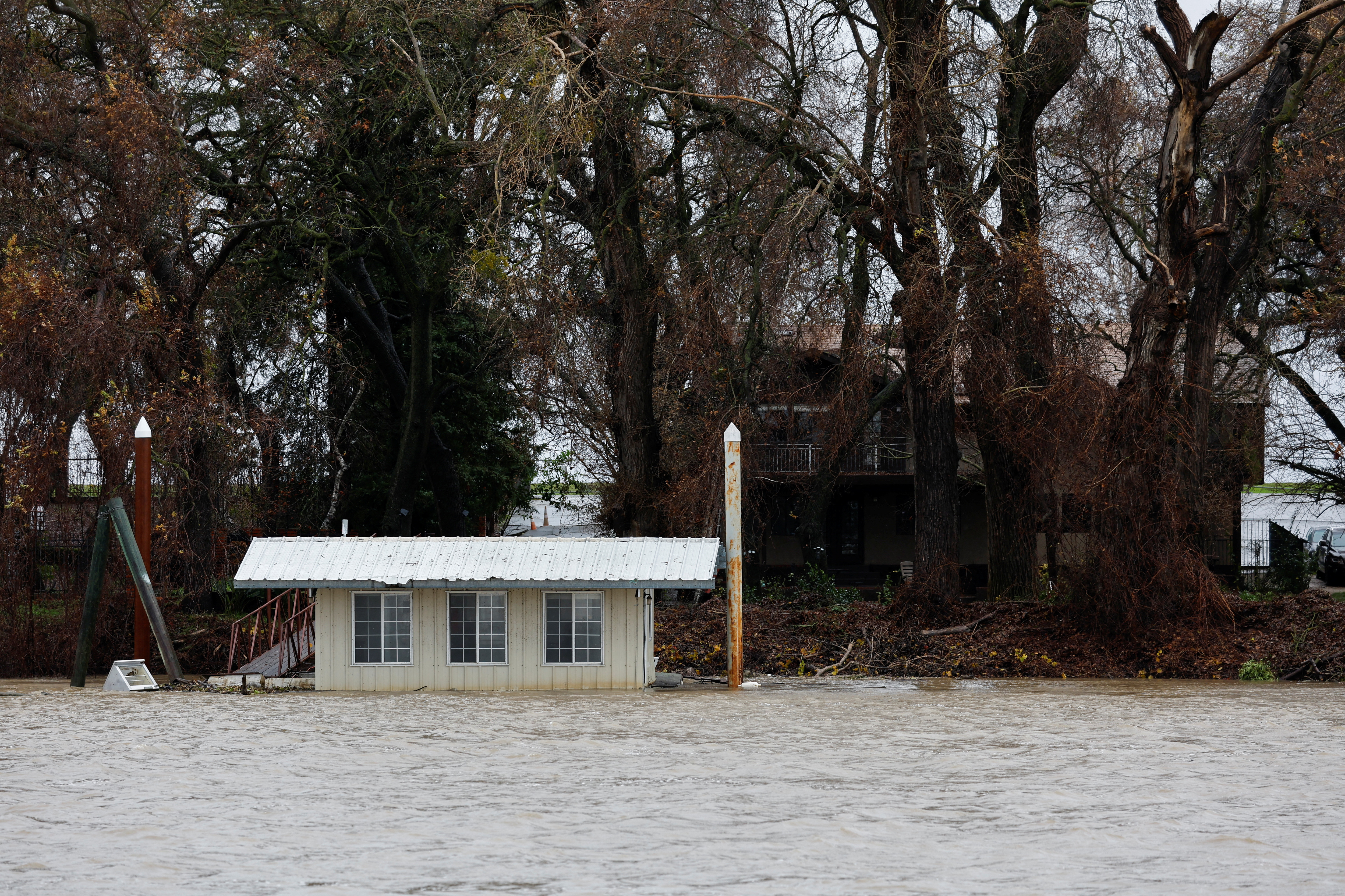 A partially submerged boathouse is seen on the Sacramento River in West Sacramento