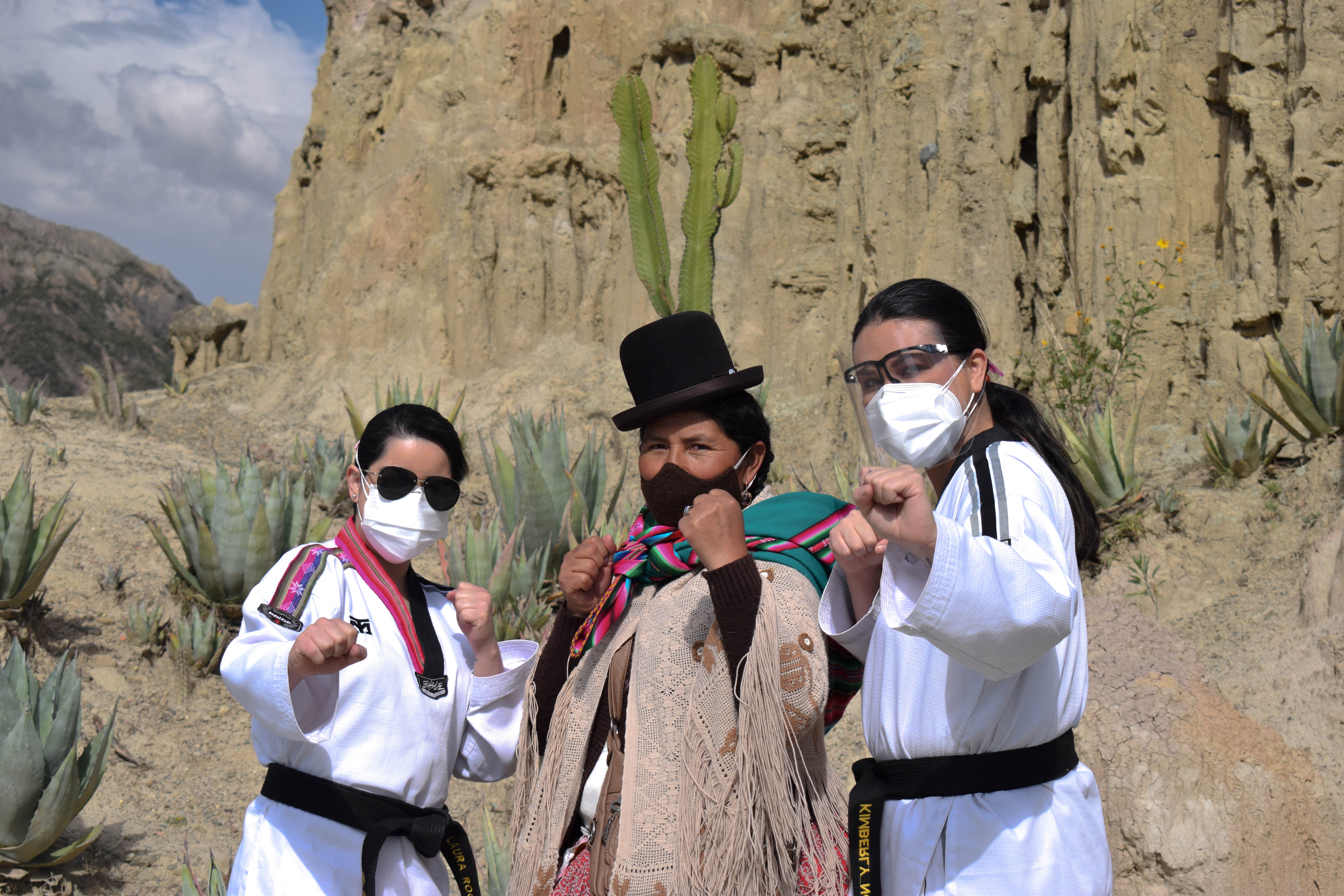 A Bolivian Aymara woman poses for a photograph with Sports Psychologist Laura Roca (L) and Personal Development and Women's coach Kimberly Nosa (R) of the Warmi Power social project during a taekwondo class to learn self-defence, on the outskirts of La Paz, Bolivia April 23, 2021. Picture taken April 23, 2021. Laura Roca/Warmi Power/Handout via REUTERS