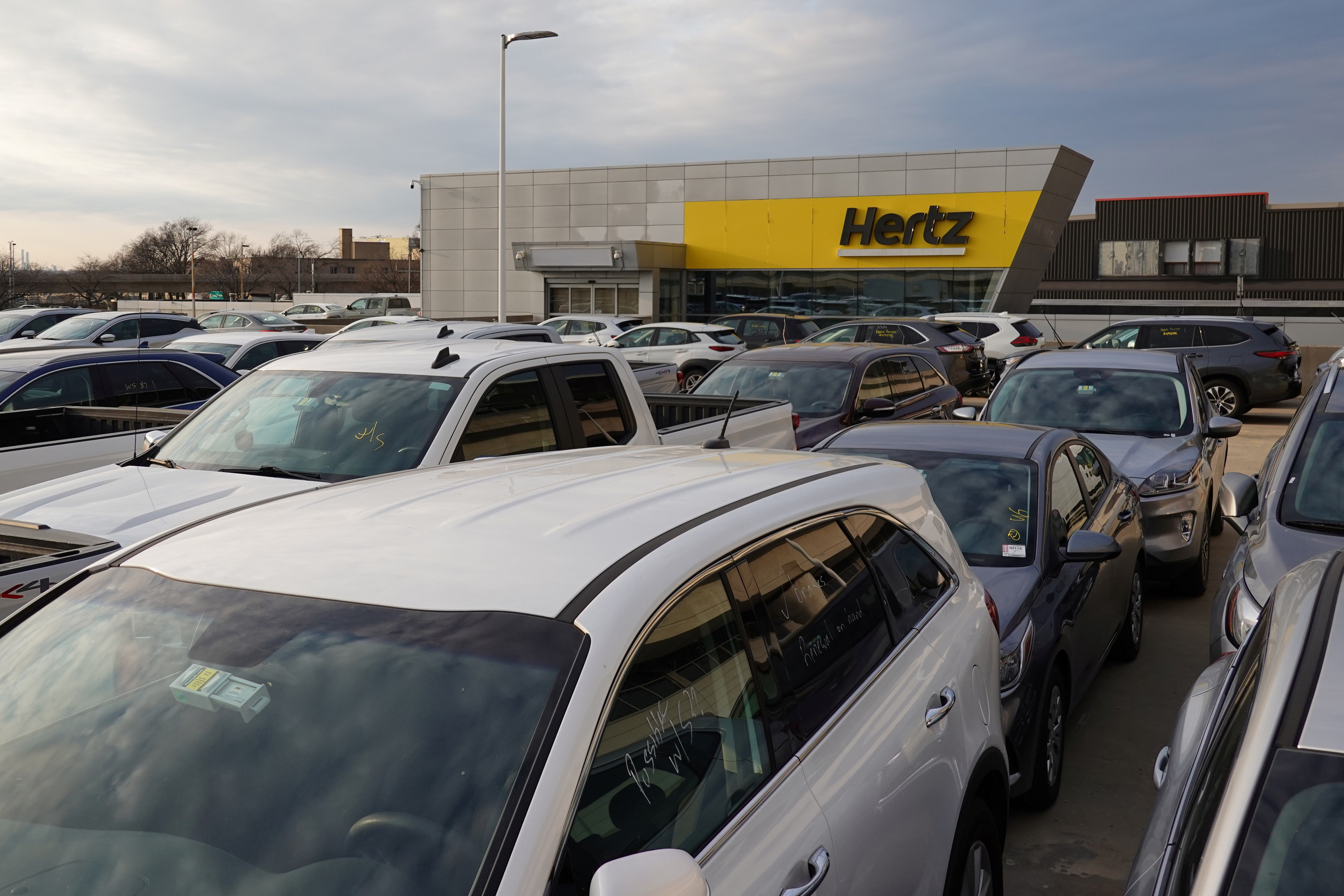 Cars are parked near Hertz car rental signage at John F. Kennedy International Airport in Queens, New York City