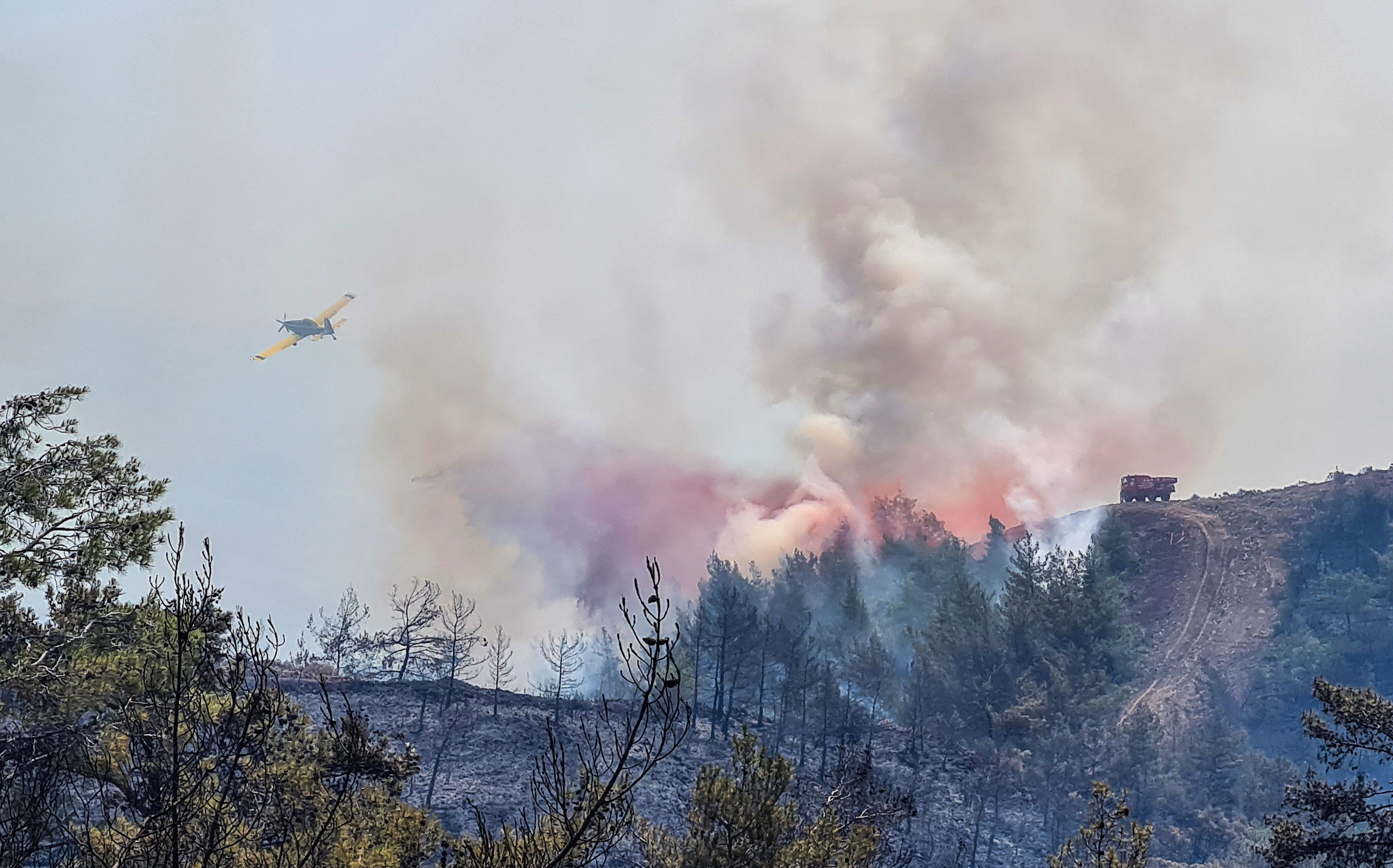 A firefighting aircraft drops water on a wildfire near Marmaris