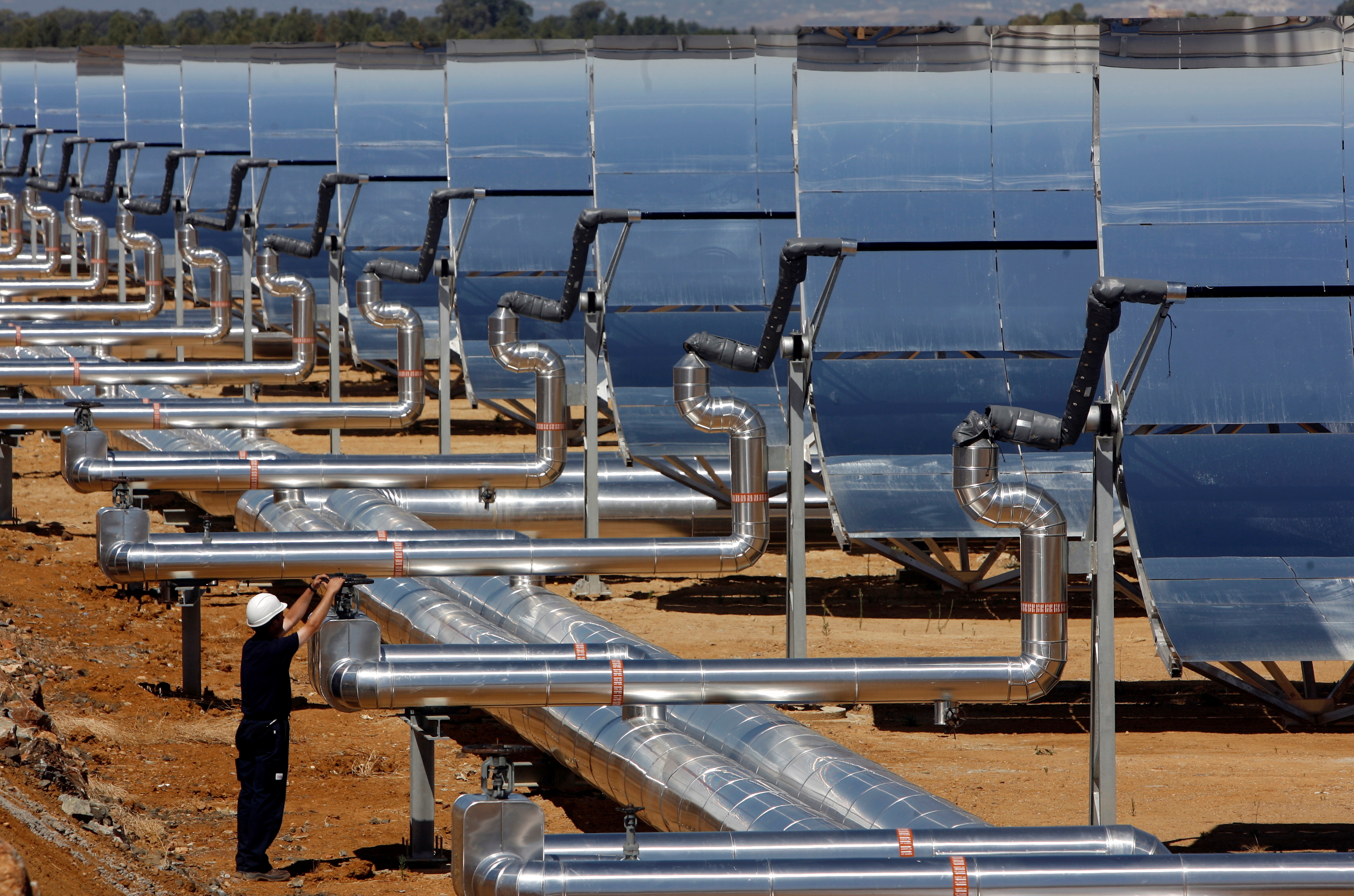 A worker makes adjustments before the inauguration ceremony of a parabolic trough solar thermal power plant in Alvarado