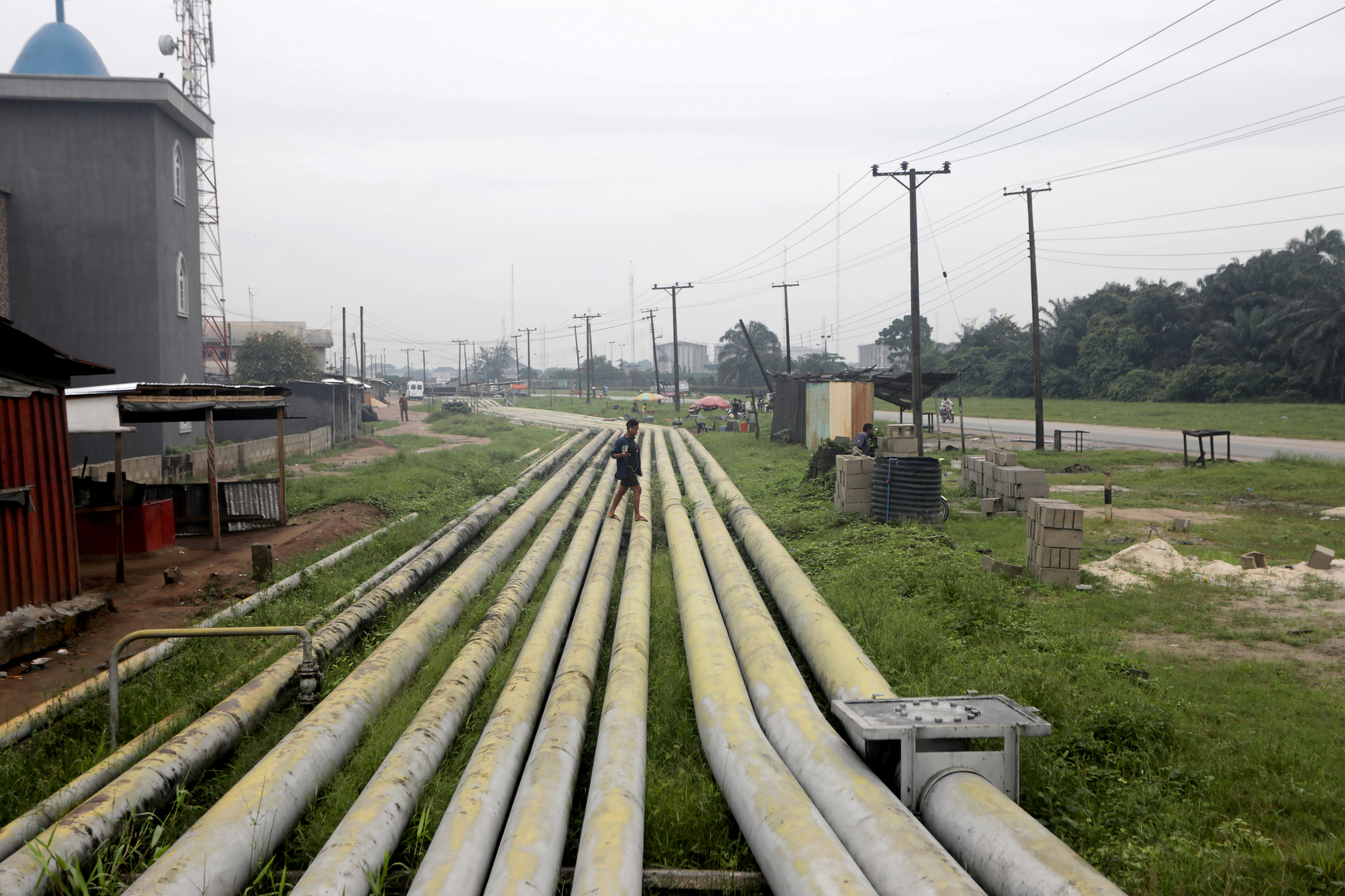 FILE PHOTO: A woman walks over pipelines crisscrossing Ogoniland in Rivers State